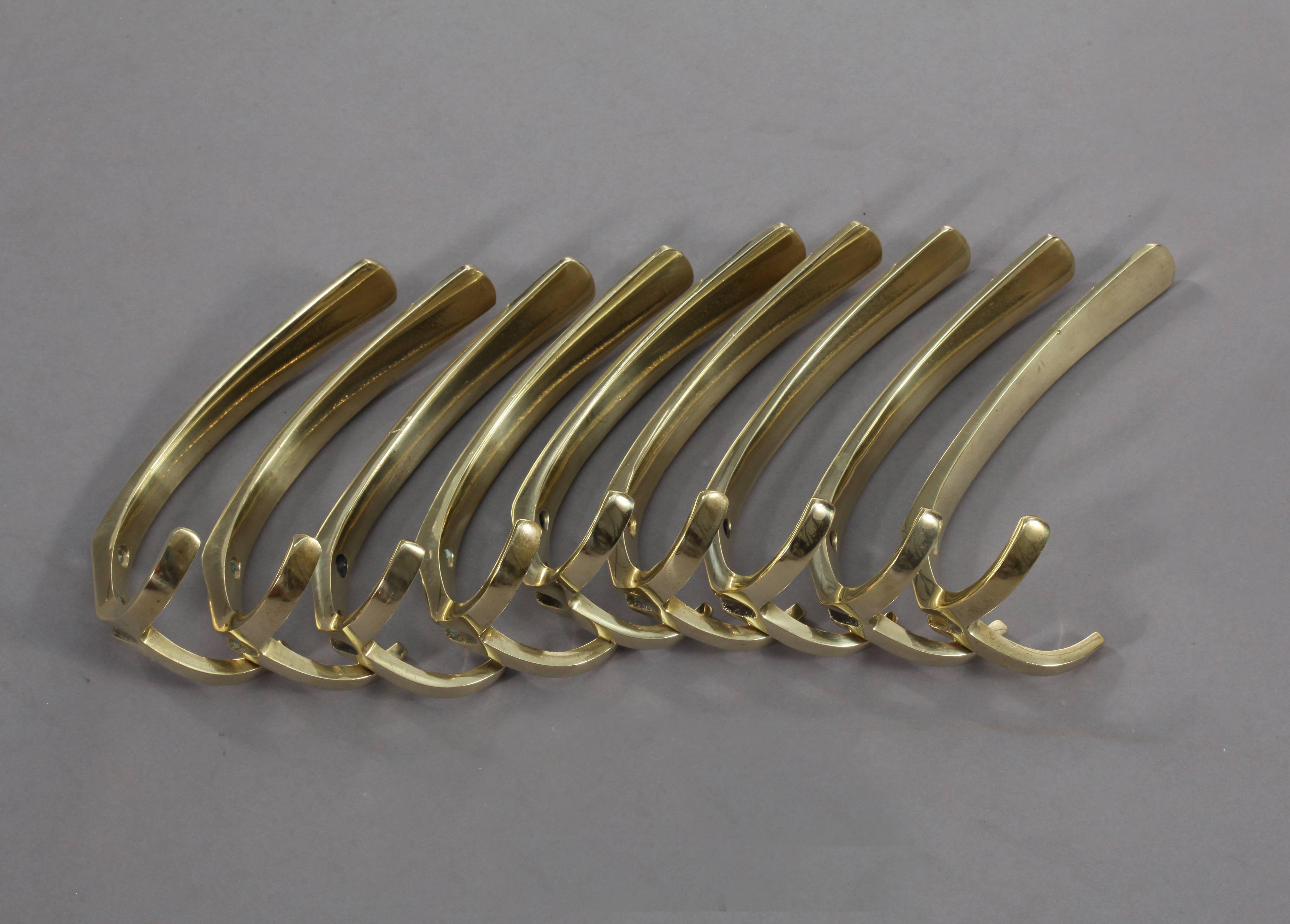 Nine simple and elegant wall-mounted brass hooks, with a contrasting faux patina. Having a large upper hook and two small lower hooks.

Designed by Carl Auböck.
Manufactured by Carl Auböck,
Vienna, 1950.
Measures: Height 6 inch (16cm), width 3