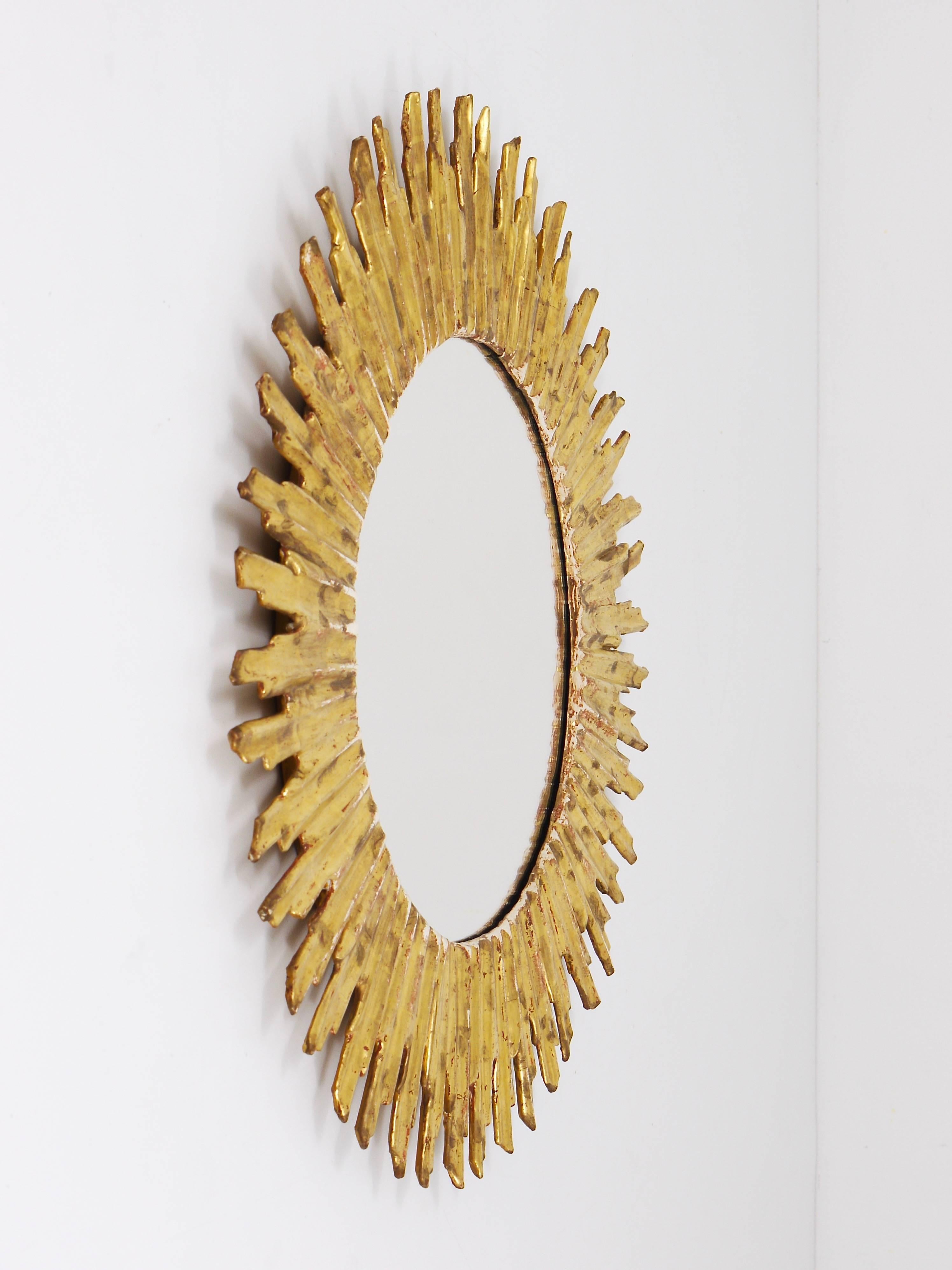 A beautiful and decorative sunburst starburst gilt wall mirror, made in France, gilded carved wood, dated circa 1950. In very good condition. Diameter 19". 
 
 