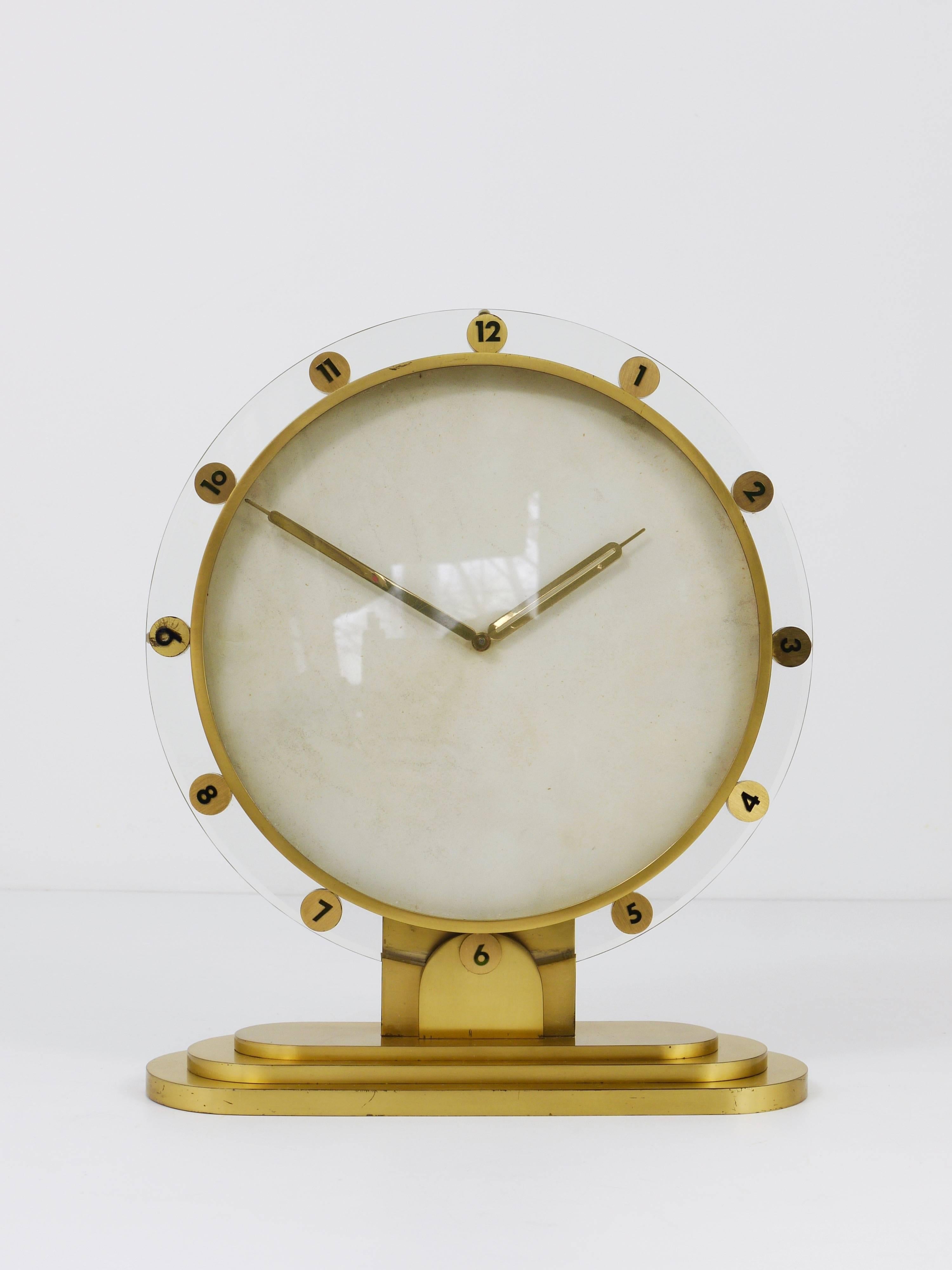 An impressive brass and glass desk or table clock with mechanical eight-day movement and a nice parchment clocks face. Made in Germany in the 1950s. An elegant and solid piece in good condition with little patina. Fully working. 

