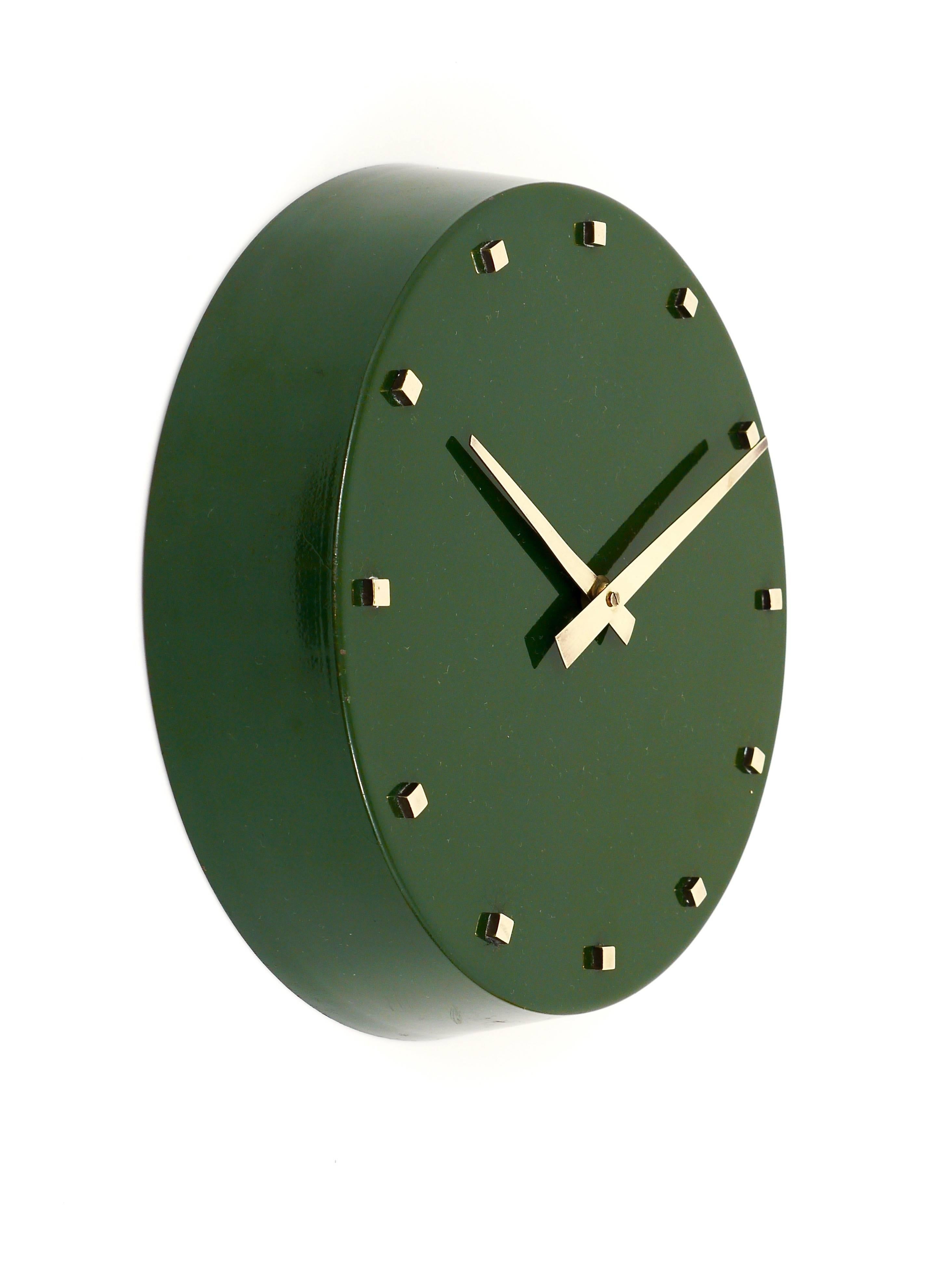 A beautiful green Mid-Century wall clock, designed by Franz Hagenauer, executed by Werkstätte Hagenauer WHW in the 1950s. This clock is completely handcrafted, it has a green lacquered metal housing and very beautiful brass hands and handmade