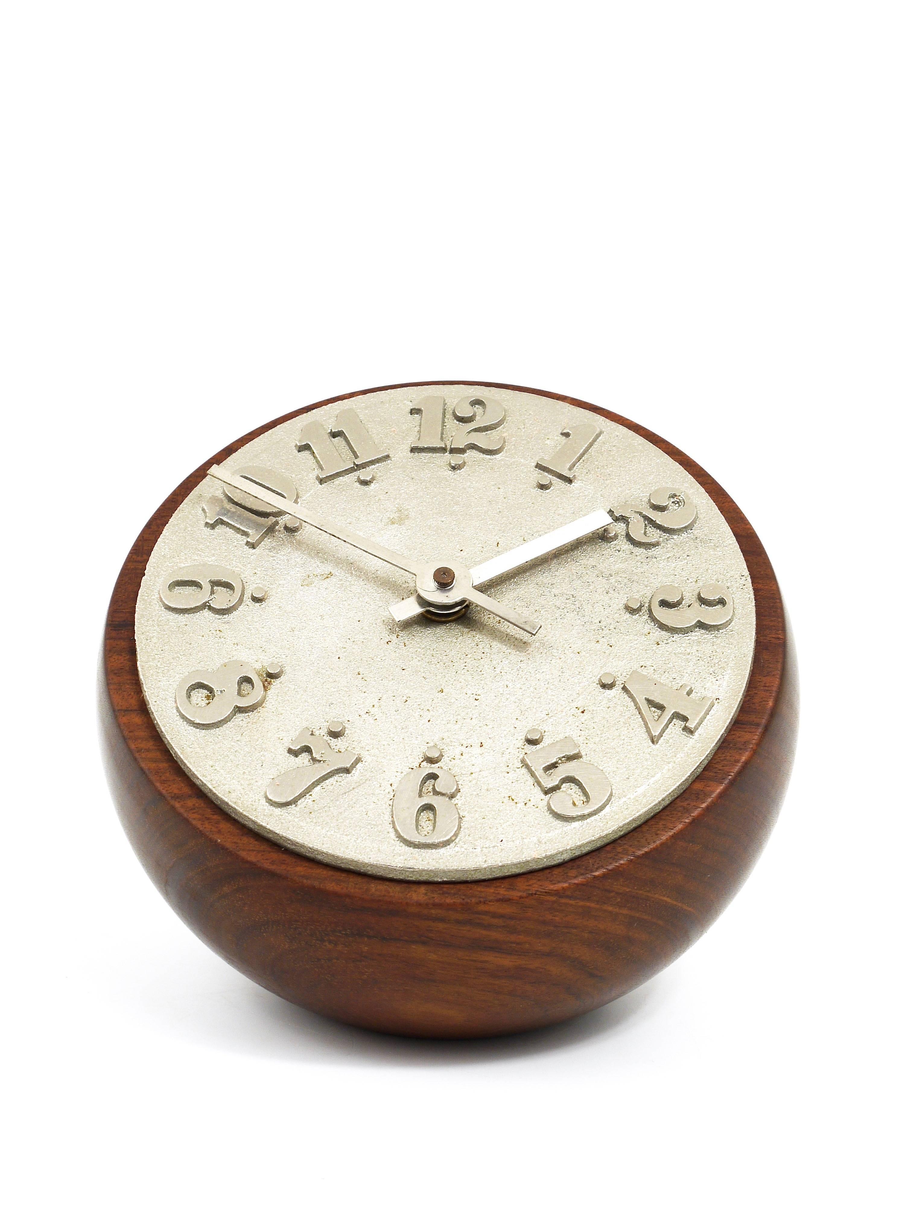 A beautiful desk or table clock, designed and executed by Carl Auböck, Austria, 1950s. Has a round housing made of walnut, the clocks face ist made of nickel-plated cast-iron. Battery-operated movement. In excellent condition. Our favourite clock.