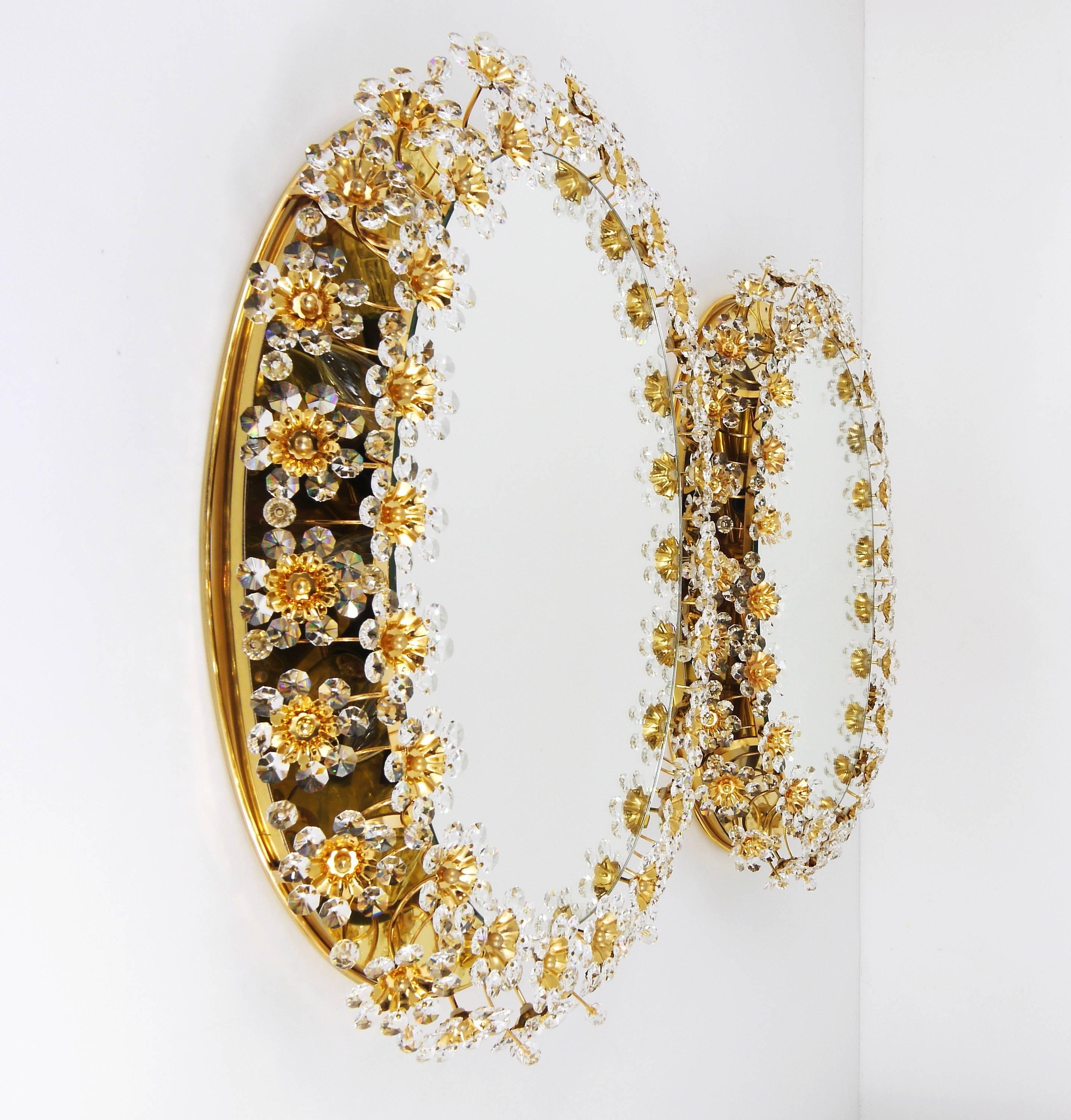 A matching pair of oval floral illuminated wall mirrors, manufactured in the 1970s by Palwa Germany. Handcrafted frame, made of gold-plated brass, covered with jewel like faceted crystal glass petals. Has ten-light sources. In excellent condition.