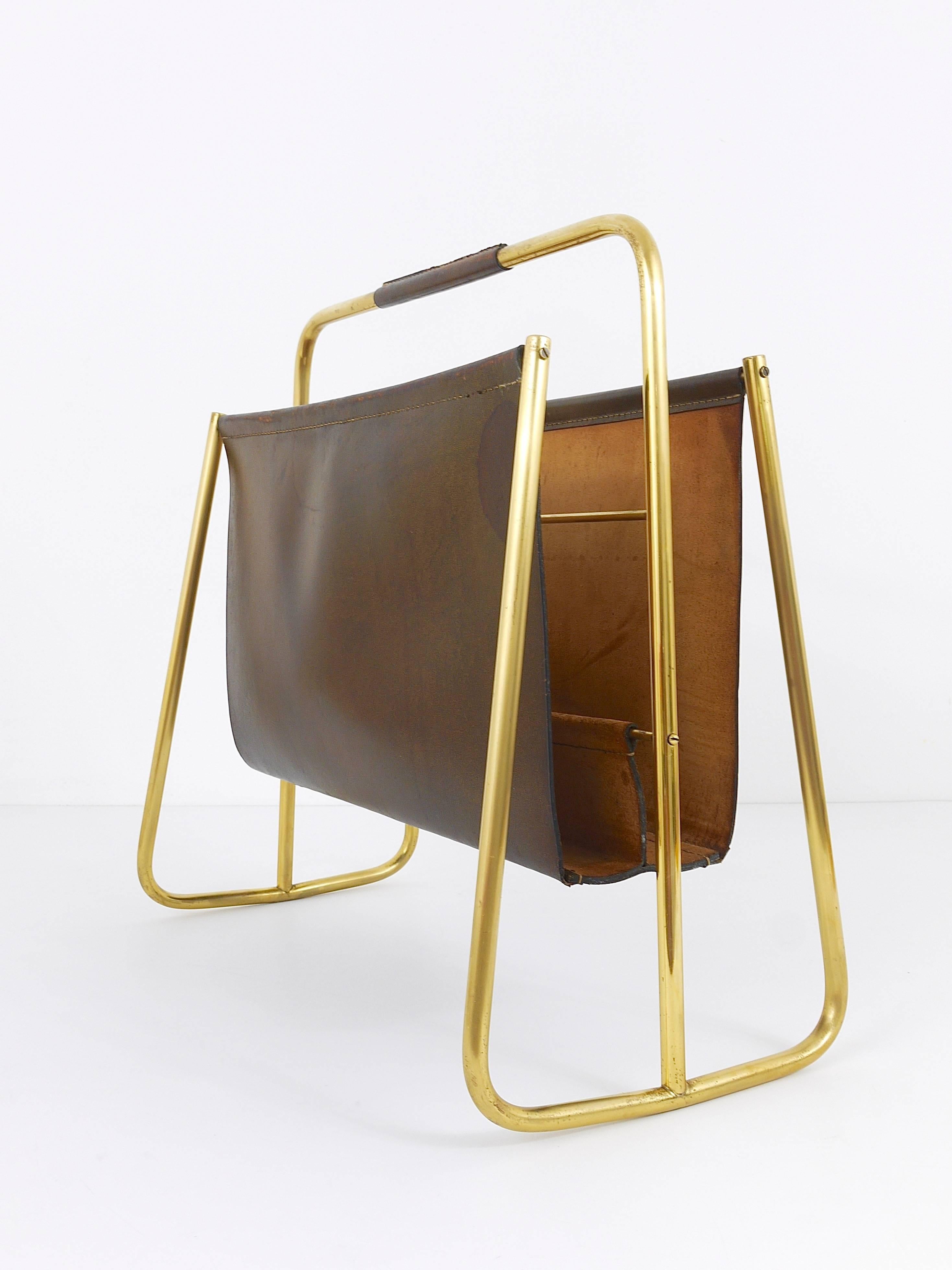 A rare and beautiful modernist magazine stand from the, designed and manufactured by Carl Auböck, Austria. In very good original condition with charming patina on the brass and the leather.