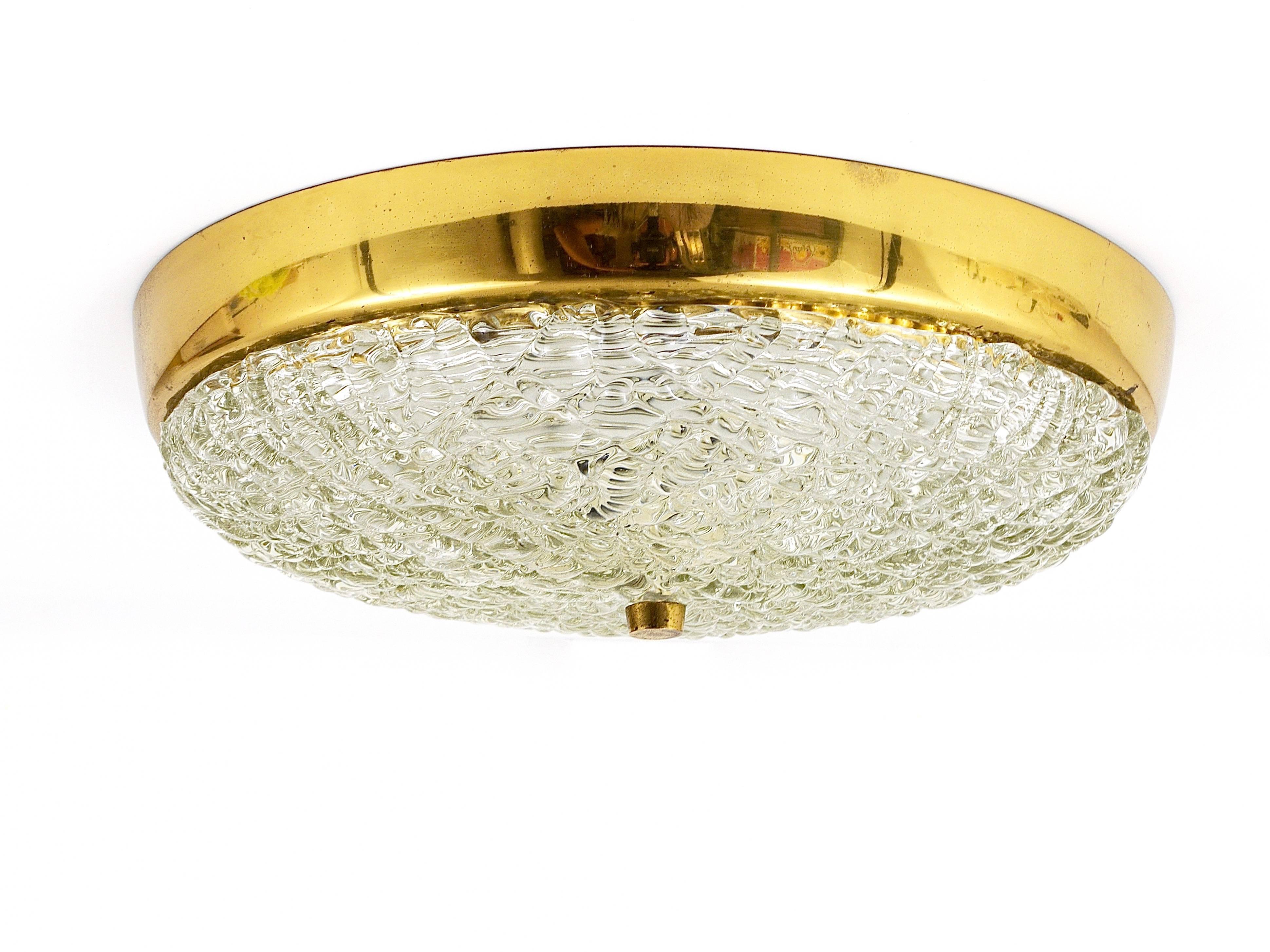 A stunning modernist flush mount lamp / ceiling light from the 1950s by Kalmar Vienna, Austria. This charming light features solid textured glass on a white metal base with a round brass frame and three light sources. It is in very good condition