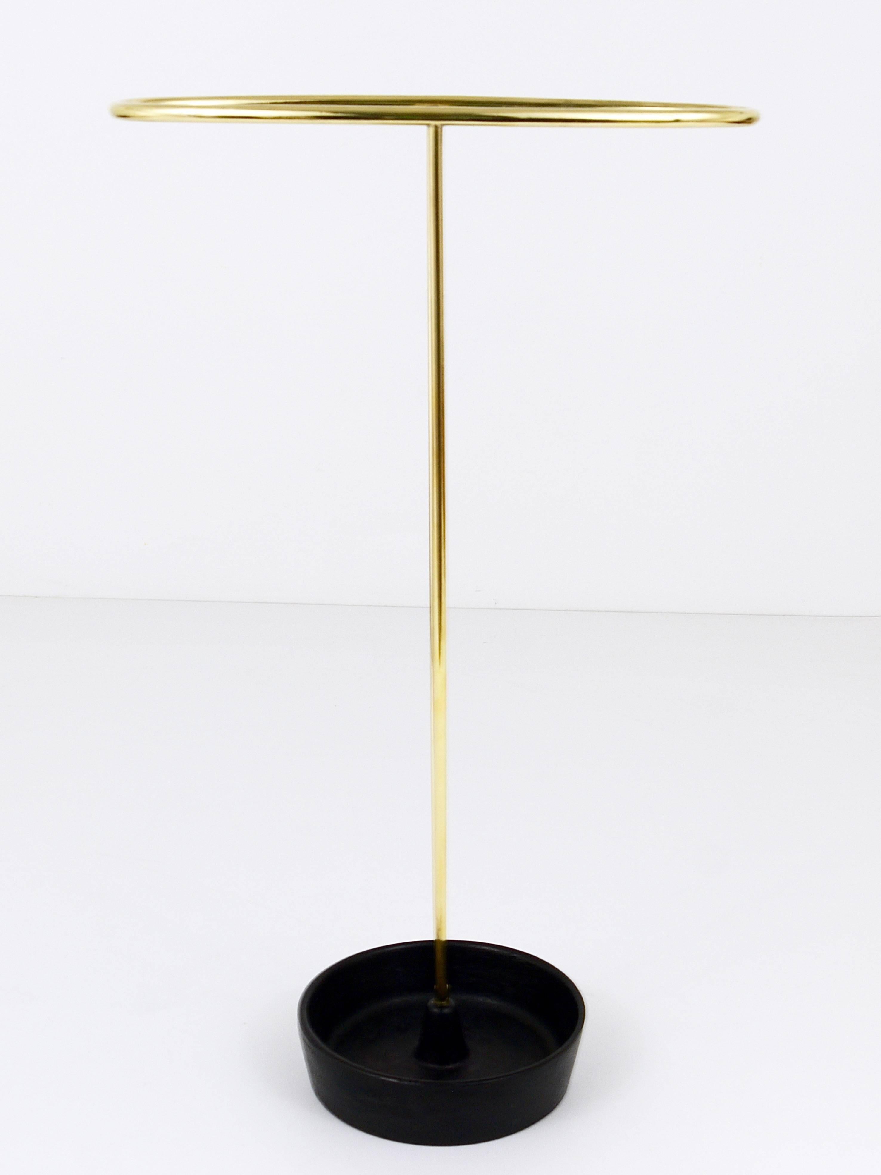 This beautiful modernist umbrella stand hails from the 1950s, crafted with brass and featuring a base of cast iron. Designed by Franz Hagenauer and executed at the Werkstätte Hagenauer Workshop in Vienna, Austria. This piece embodies a blend of