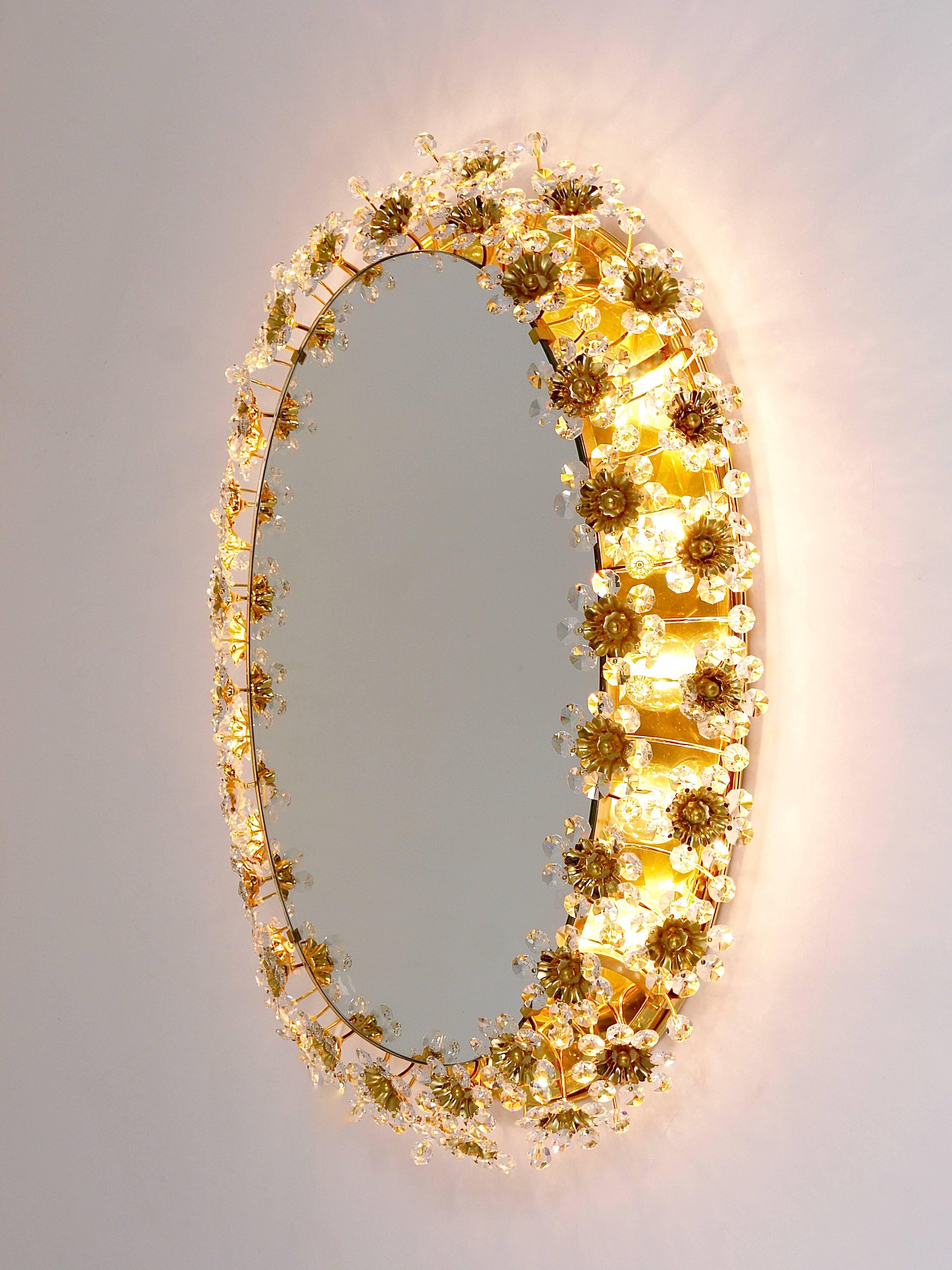 A beautiful oval floral illuminated wall mirror, manufactured in the 1970s by Palwa Germany. Handcrafted frame, made of gold-plated brass, covered with jewel like faceted crystal glass petals. Has ten-light sources. In excellent condition. Please