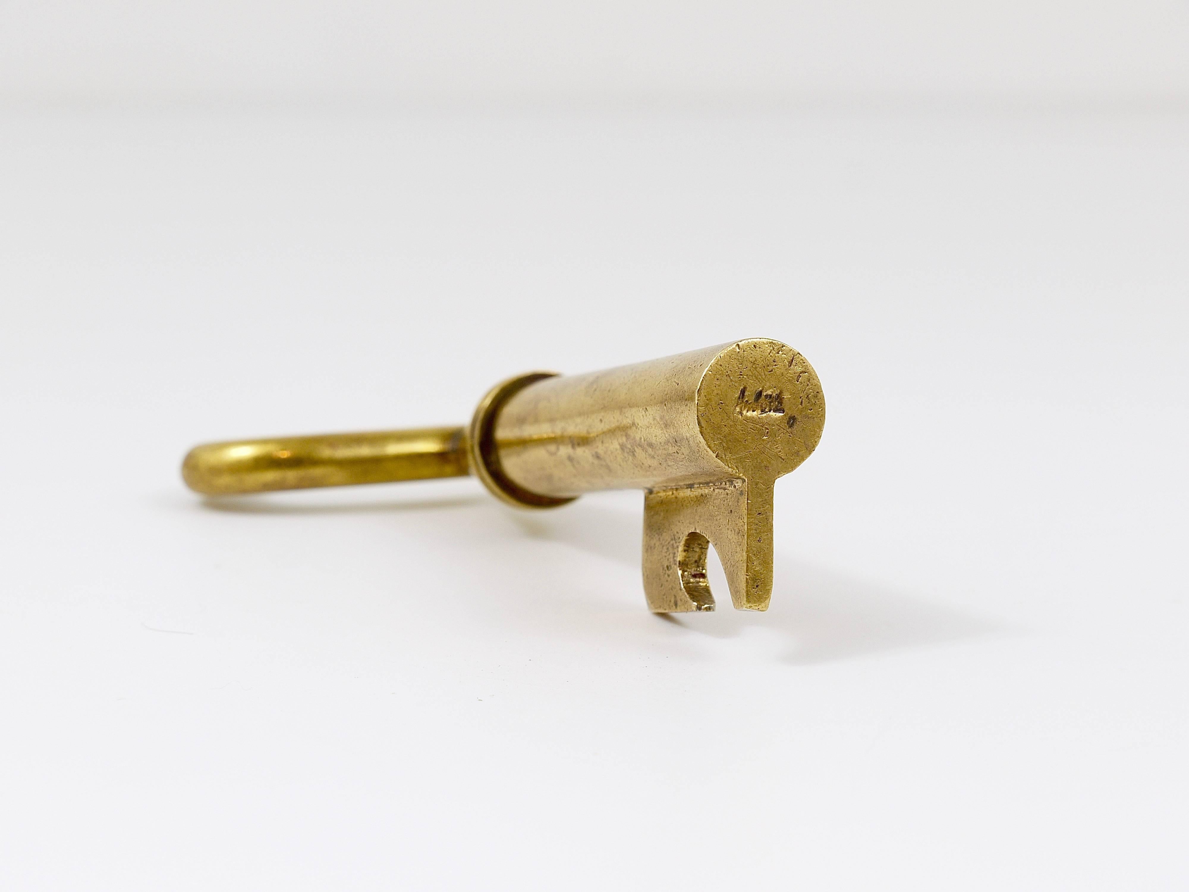 A Midcentury combination corkscrew, bottle opener, and paperweight dating from the 1950s. Shaped like a large key, it was designed by Carl Auböck and crafted by his workshop in Vienna, Austria. This vintage piece is made of solid brass, showing a