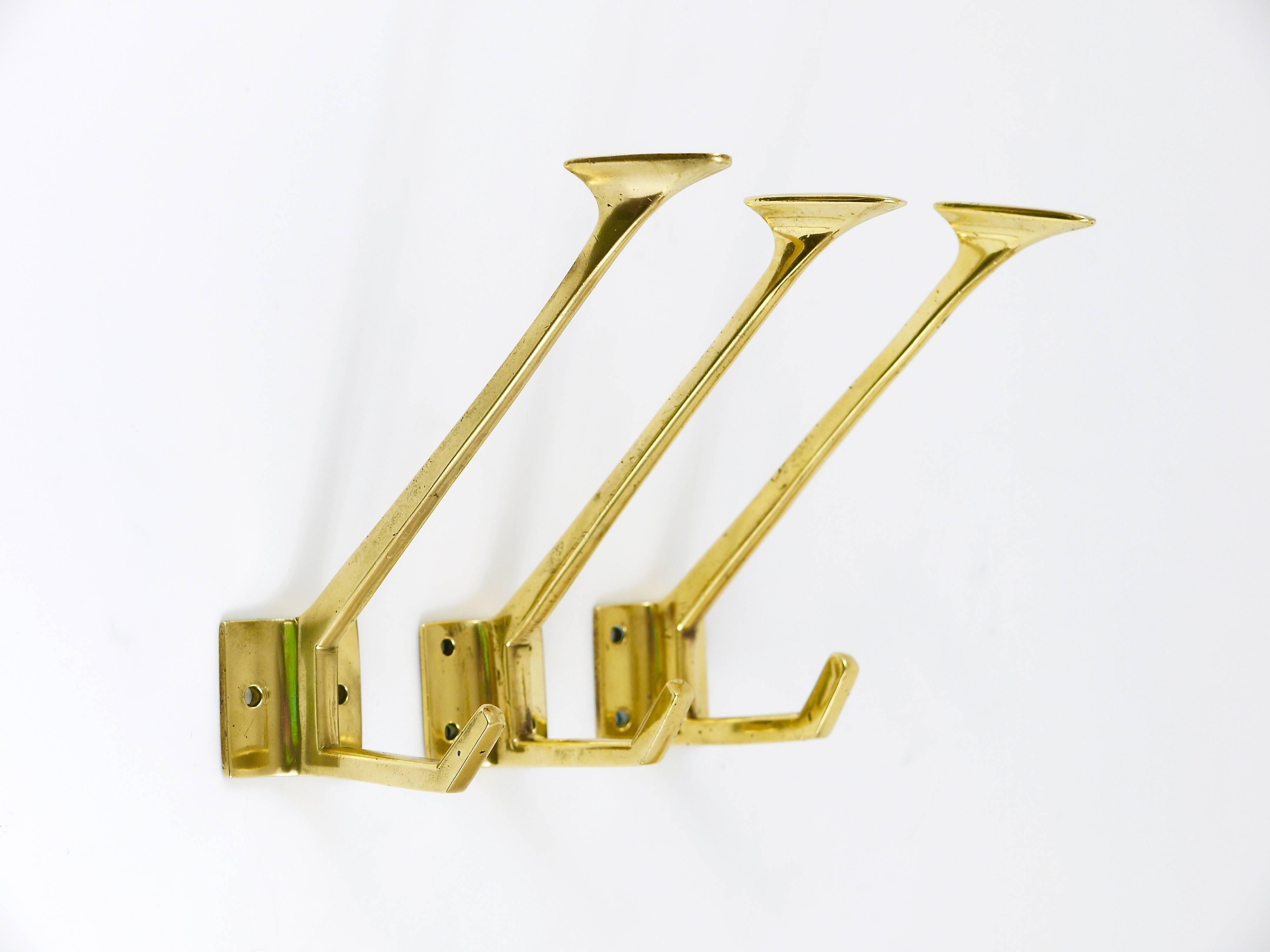 Three beautiful wall coat hooks, handmade of solid brass, dated circa 1910-1920 in Vienna, Austria. Gently polished by hand, in good condition with nice patina. Sold as a set of three.