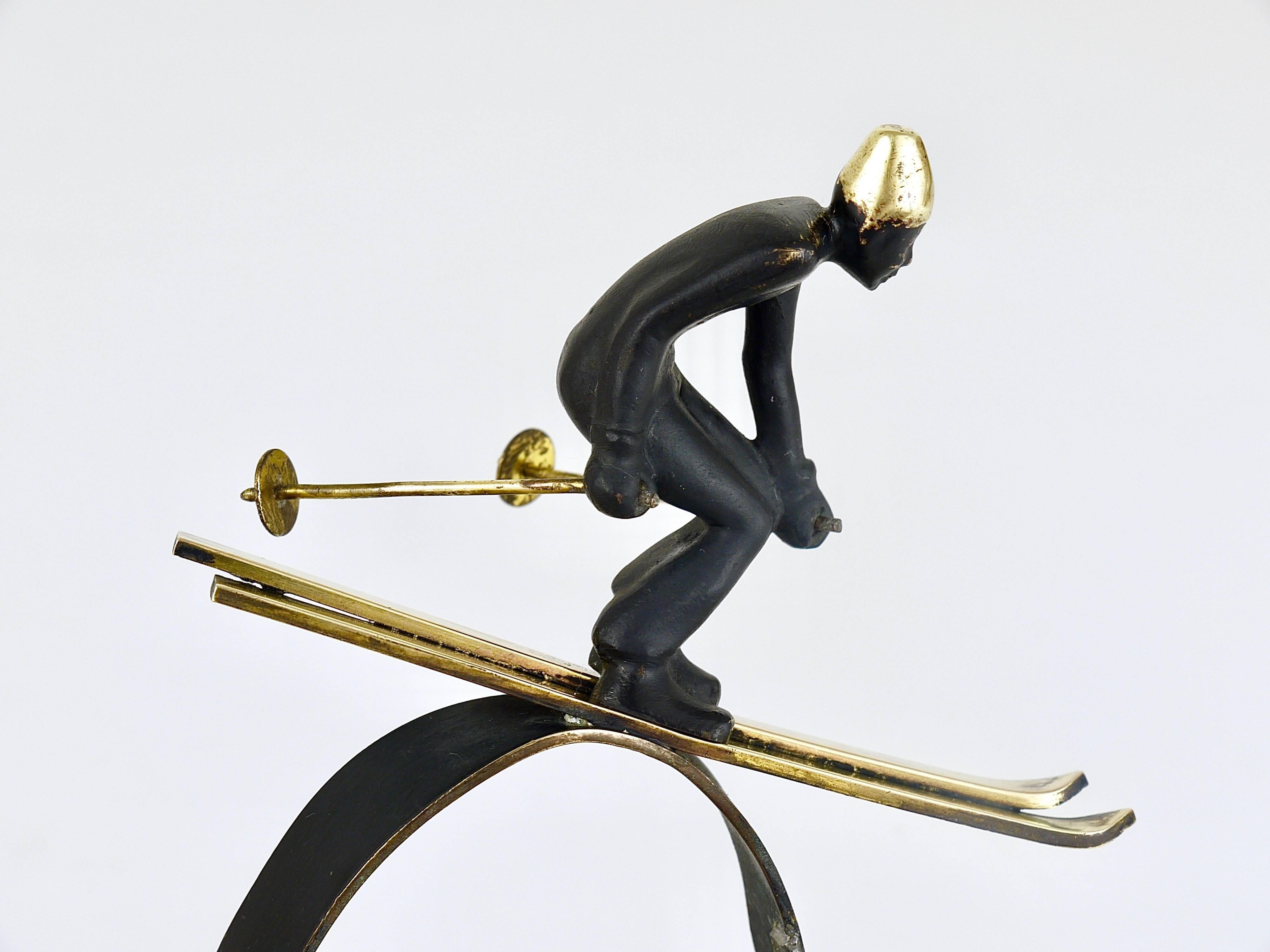 A decorative and rare Mid-Century brass sculpture, displaying a skier on a hill with trees from the 1950s. Designed by Walter Bosse, executed by Hertha Baller in Austria. In good condition with charming patina. We offer other Walter Bosse brass