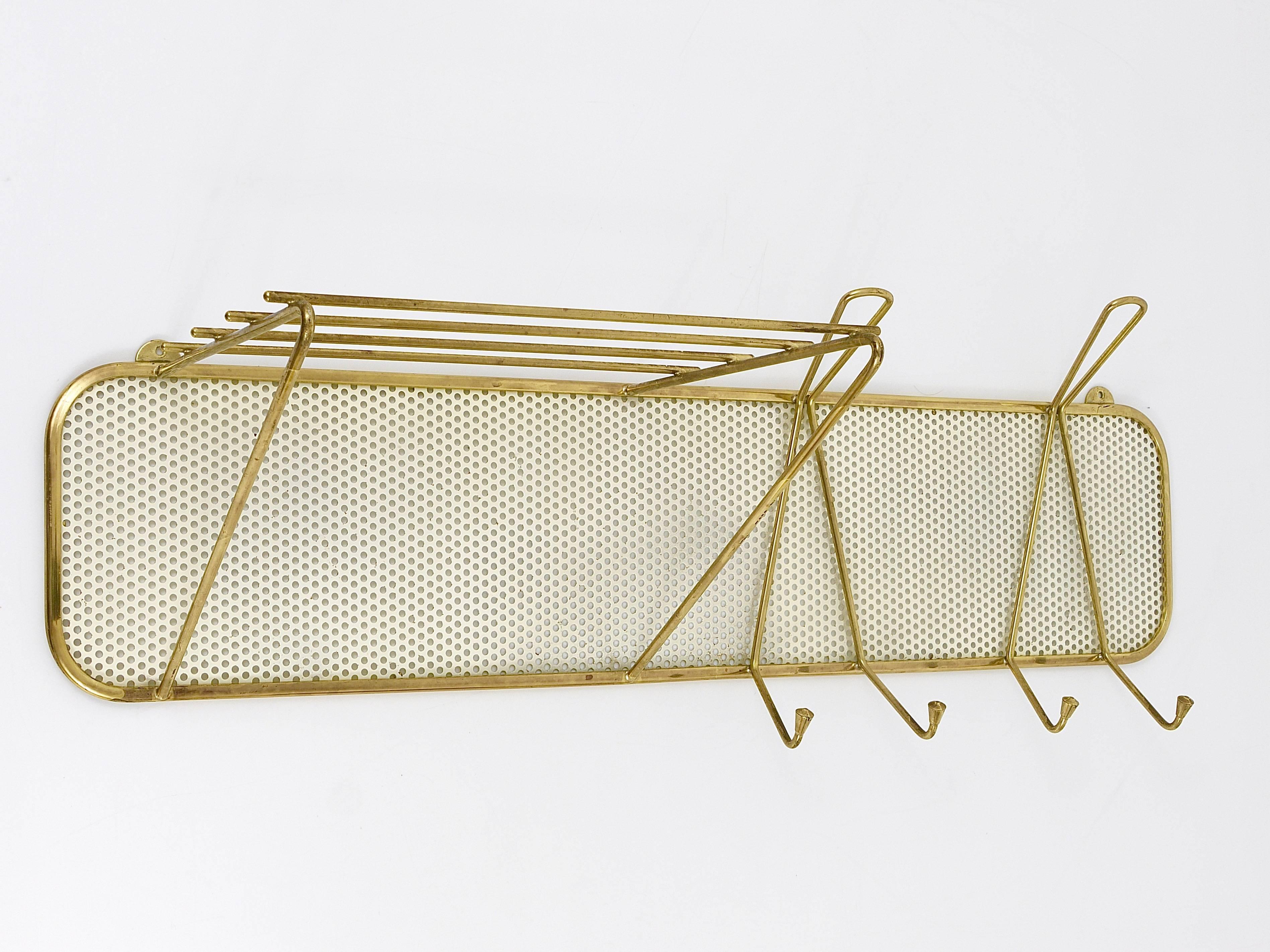 A beautiful modernist coat and hat wall racks from the 1950s. Manufactured by Münchner Werkstätten, Germany. Made of brass and white lacquered perforated metal sheet. In good condition with nice patina on the brass.