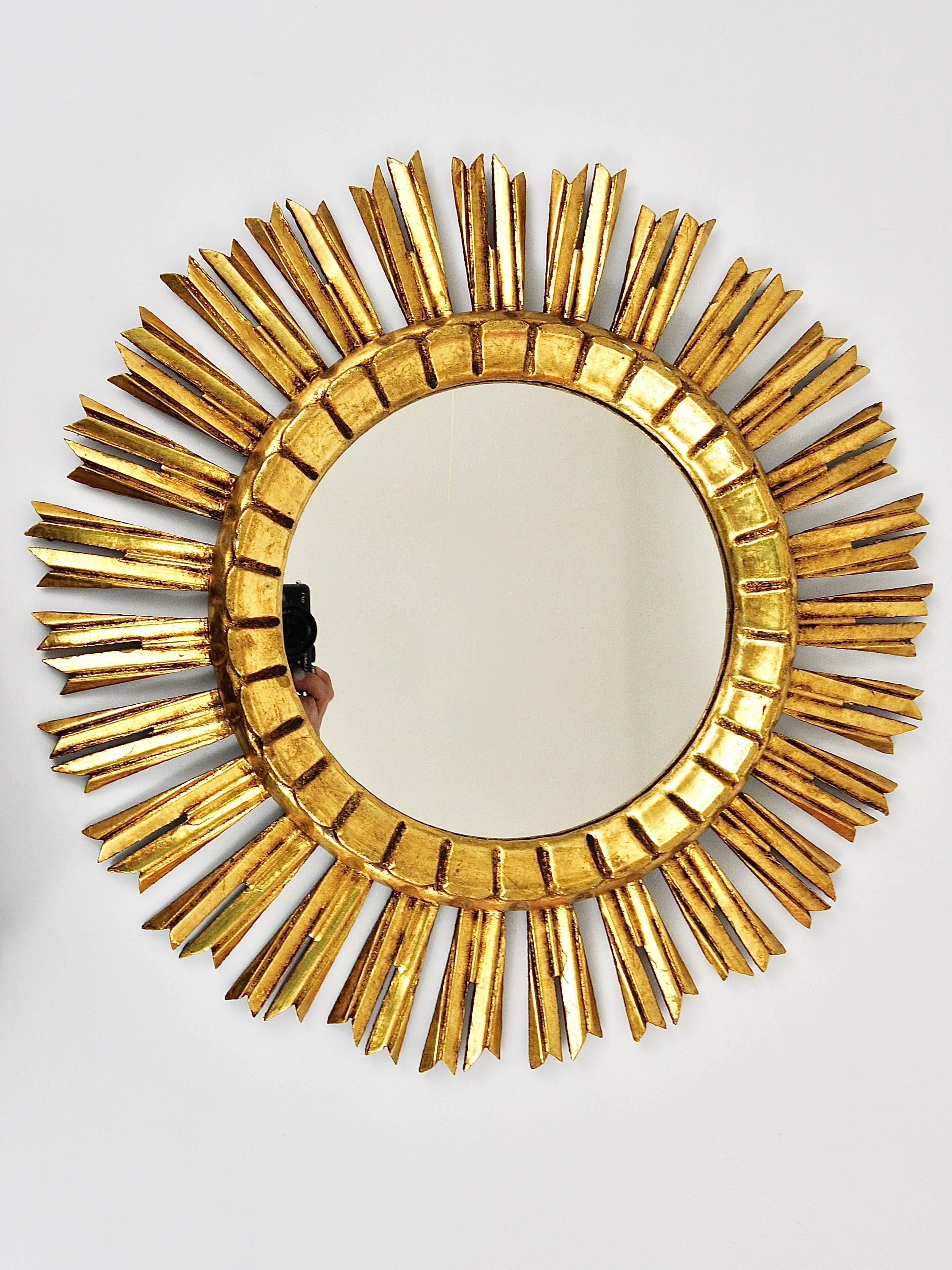 A beautiful and decorative sunburst/starburst gilt wall mirror from France, carved wood, dated around 1950. In very good condition. Diameter 20