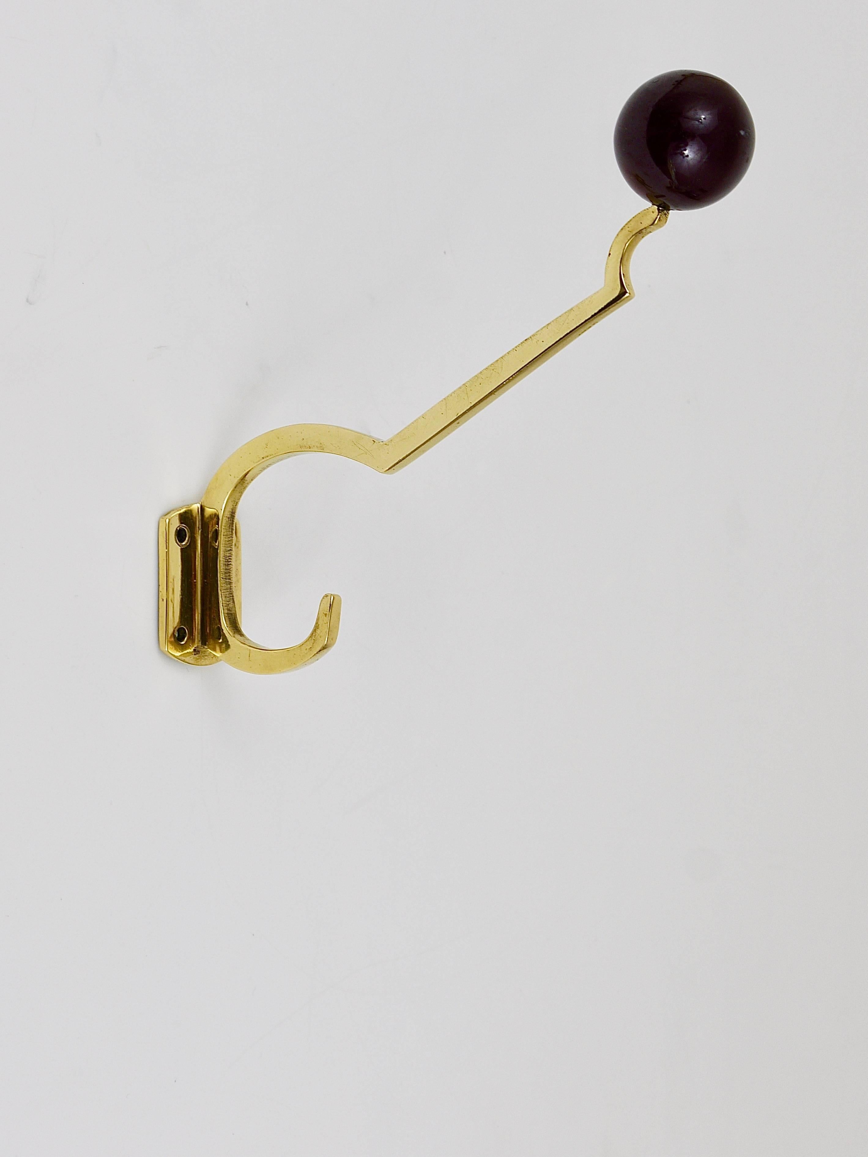 Up to three beautiful wall coat hooks, handmade of solid brass with nice bakelite balls on their top, dated around 1910-1920, made in Vienna, Austria. Gently polished by hand, in good condition with nice patina. Three hooks are available, sold and