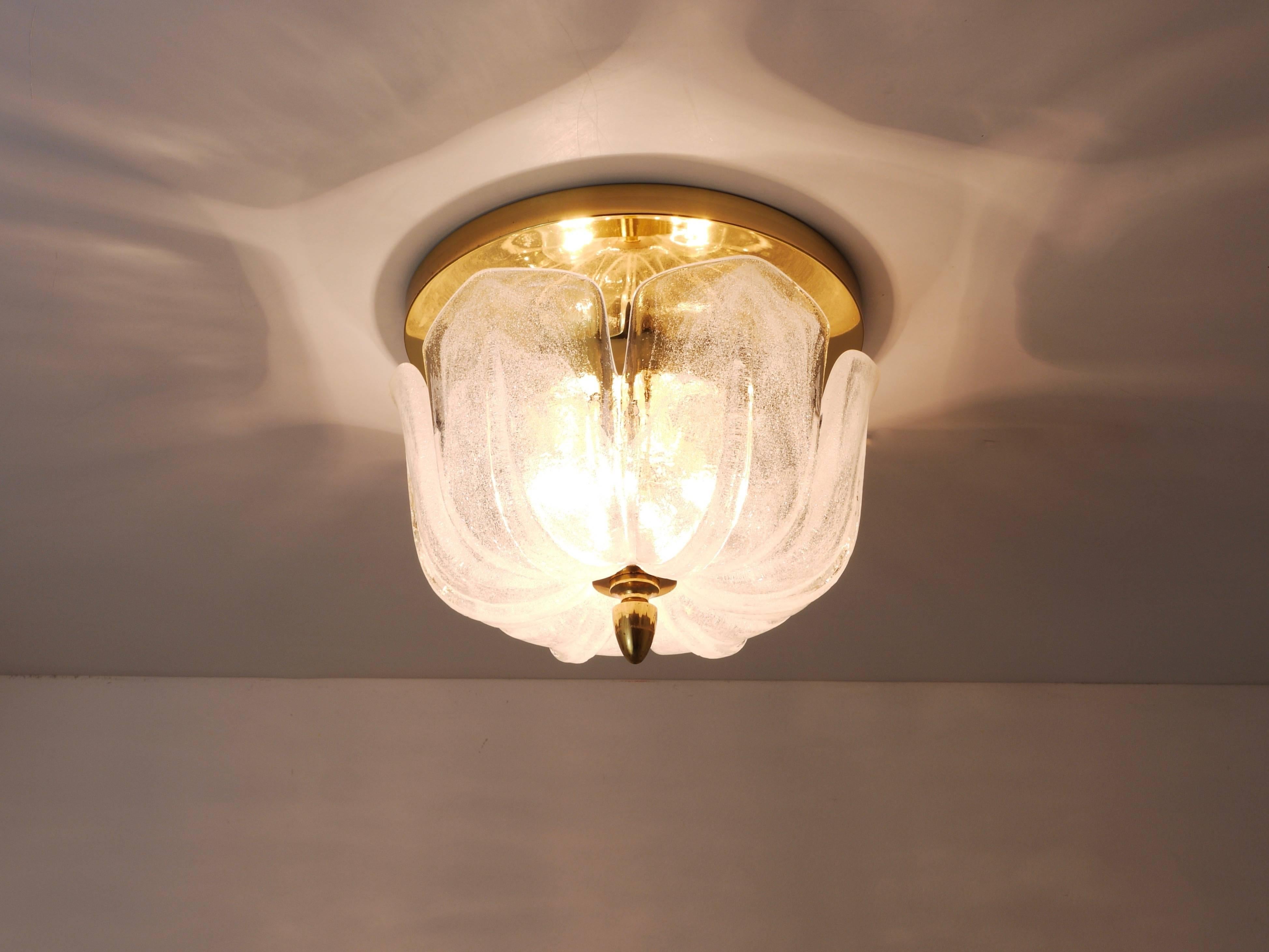 A beautiful ceiling light or flush mount from the 1970s, executed by Limburg, Germany. It has a brass base with three light sources and a beautiful round melting glass or ice glass lampshade. In good condition with marginal patina on the brass. 
 