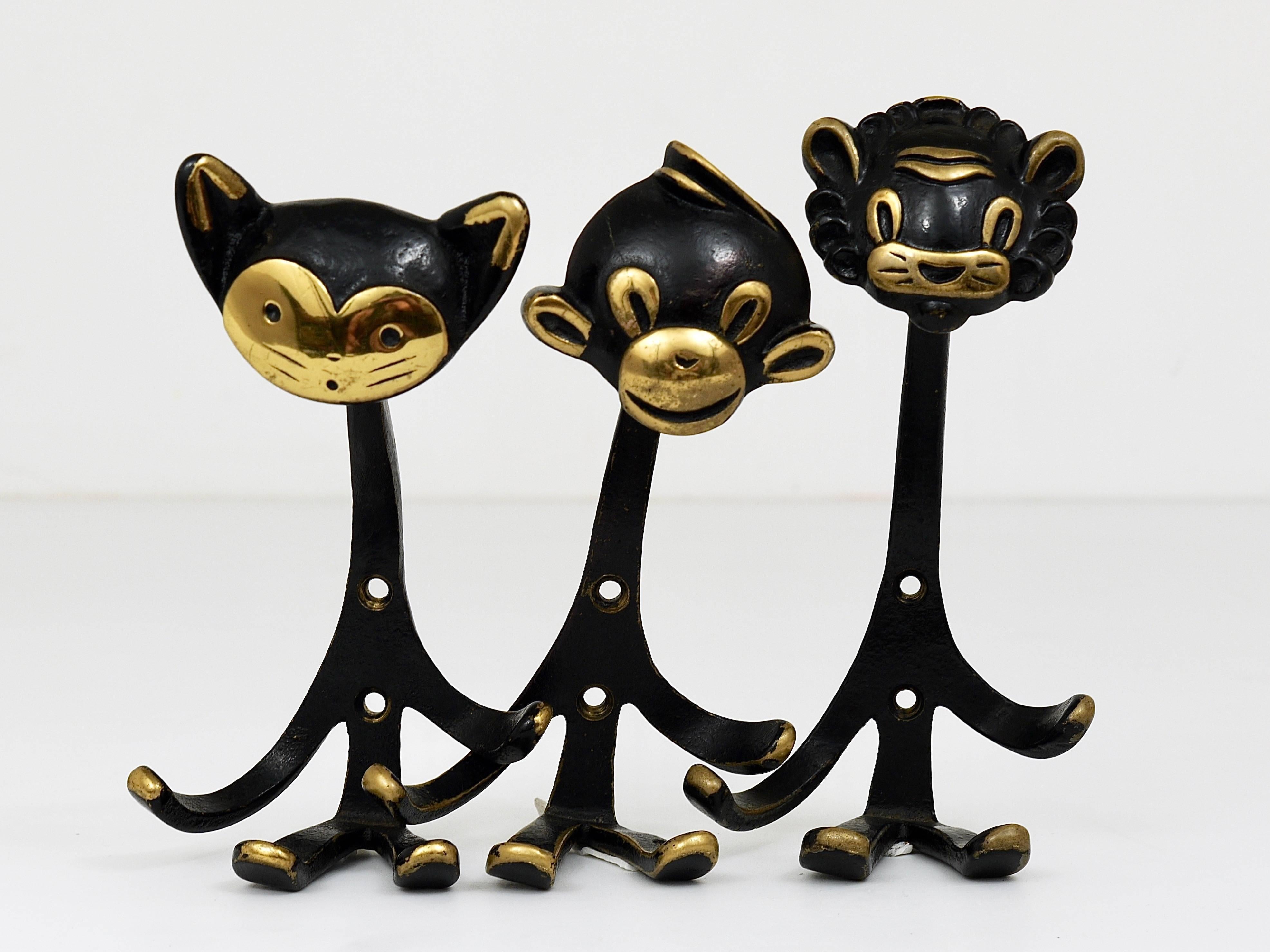 A set of three Mid-Century brass wall coat hooks, displaying a cat, a lion and a monkey. A very humorous design by Walter Bosse, executed by Hertha Baller Austria in the 1950s. Made of black finished brass. In good condition with nice patina. Each