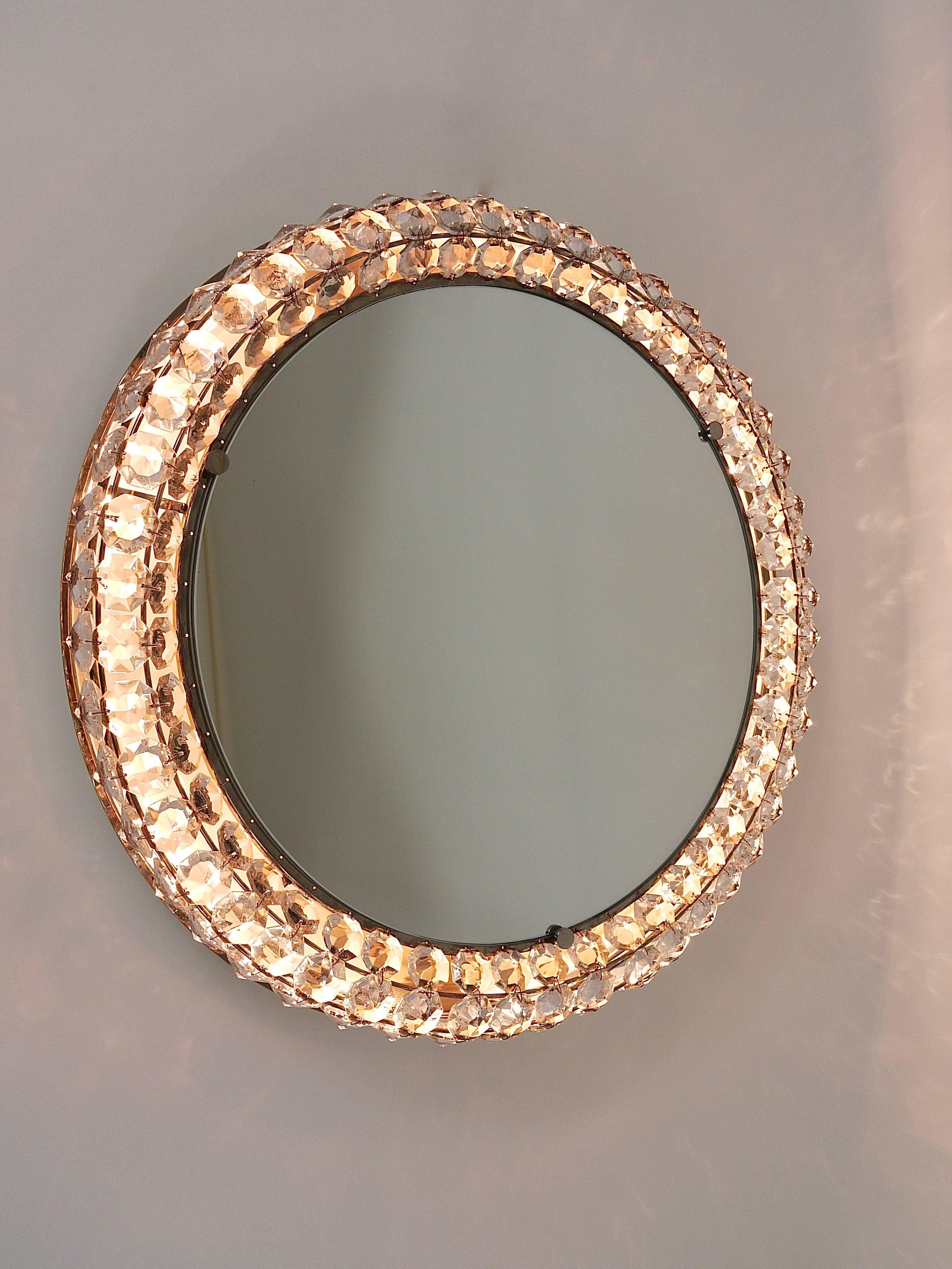 A beautiful round Mid-Century wall mirror with a frame covered with three rows of diamond-shaped faceted crystals. Designed and executed by Bakalowits & Sohne in the 1950s. Incredible good quality, nickel-plated metal. The mirror takes up to 4