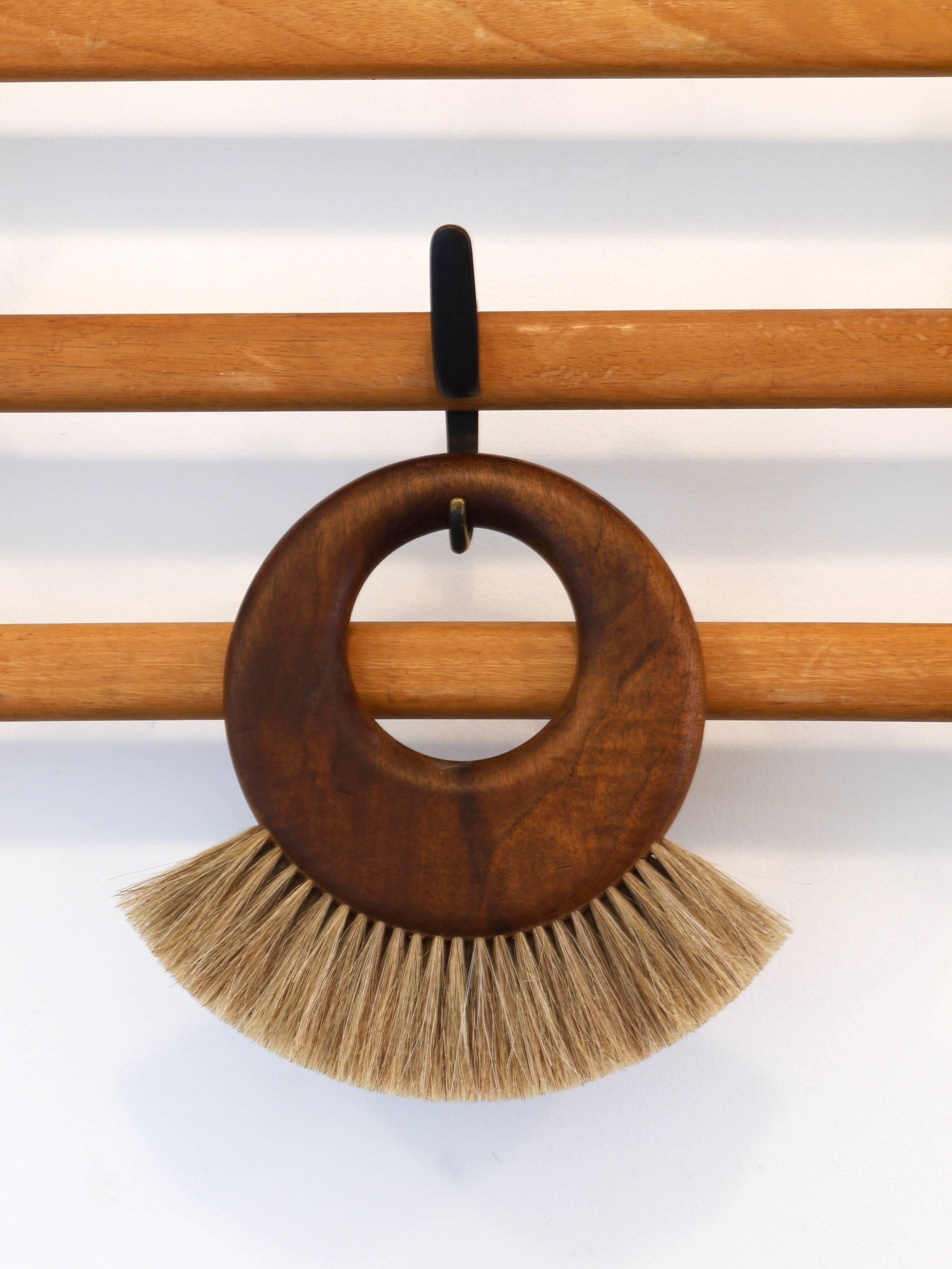 A beautiful ring-shaped modernist wall-hung clothes brush from the 1950s. Designed and executed by Carl Aubock, Vienna, in the 1950s. Made of walnut and natural bristles. In very good condition with nice patina.