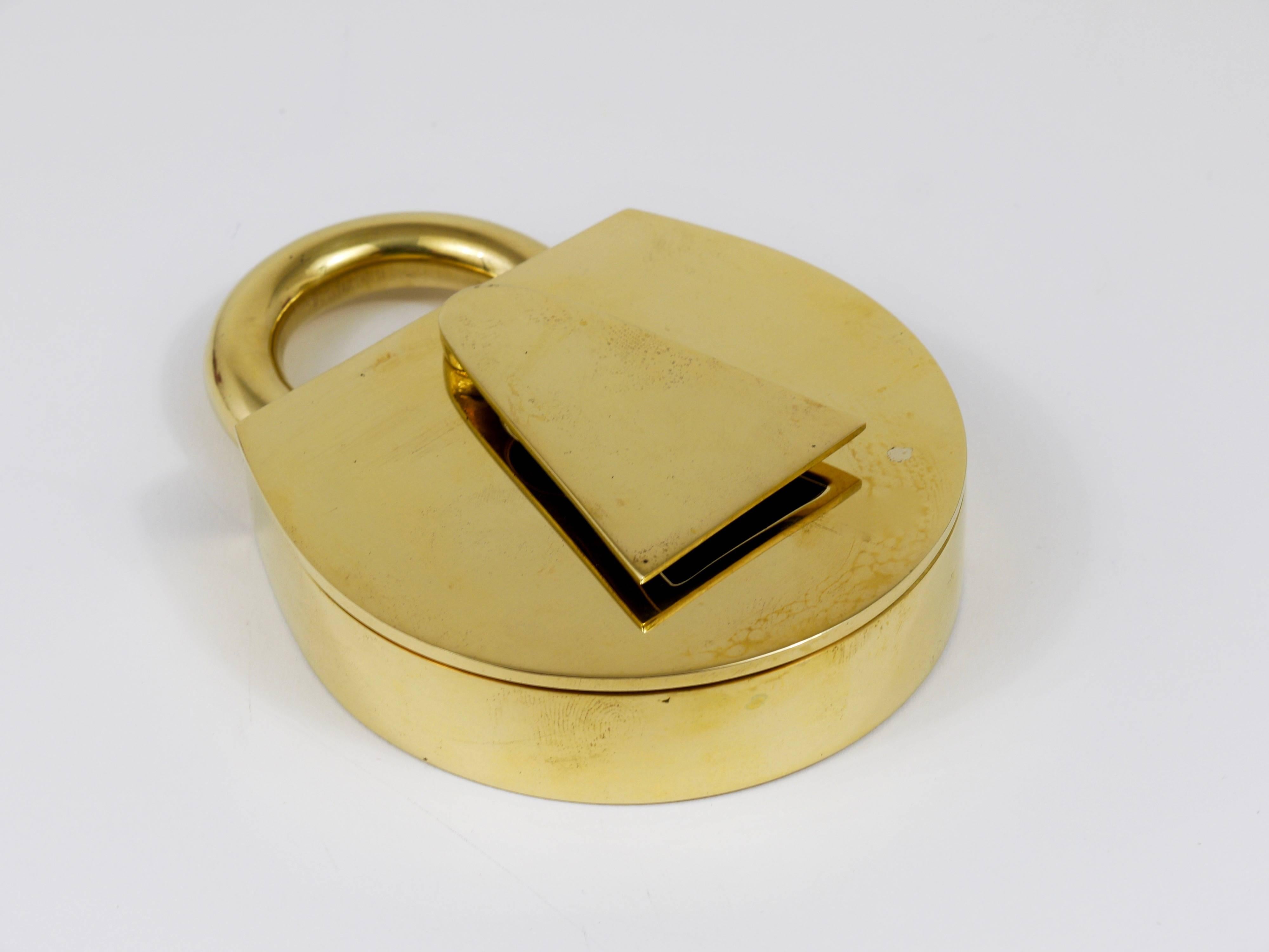 A beautiful Mid-Century Modernist brass ashtray in the shape of a padlock. Designed and executed by Carl Aubock in Austria. Carefully polished, in excellent condition with marginal and charming signs of age. Marked. 

 