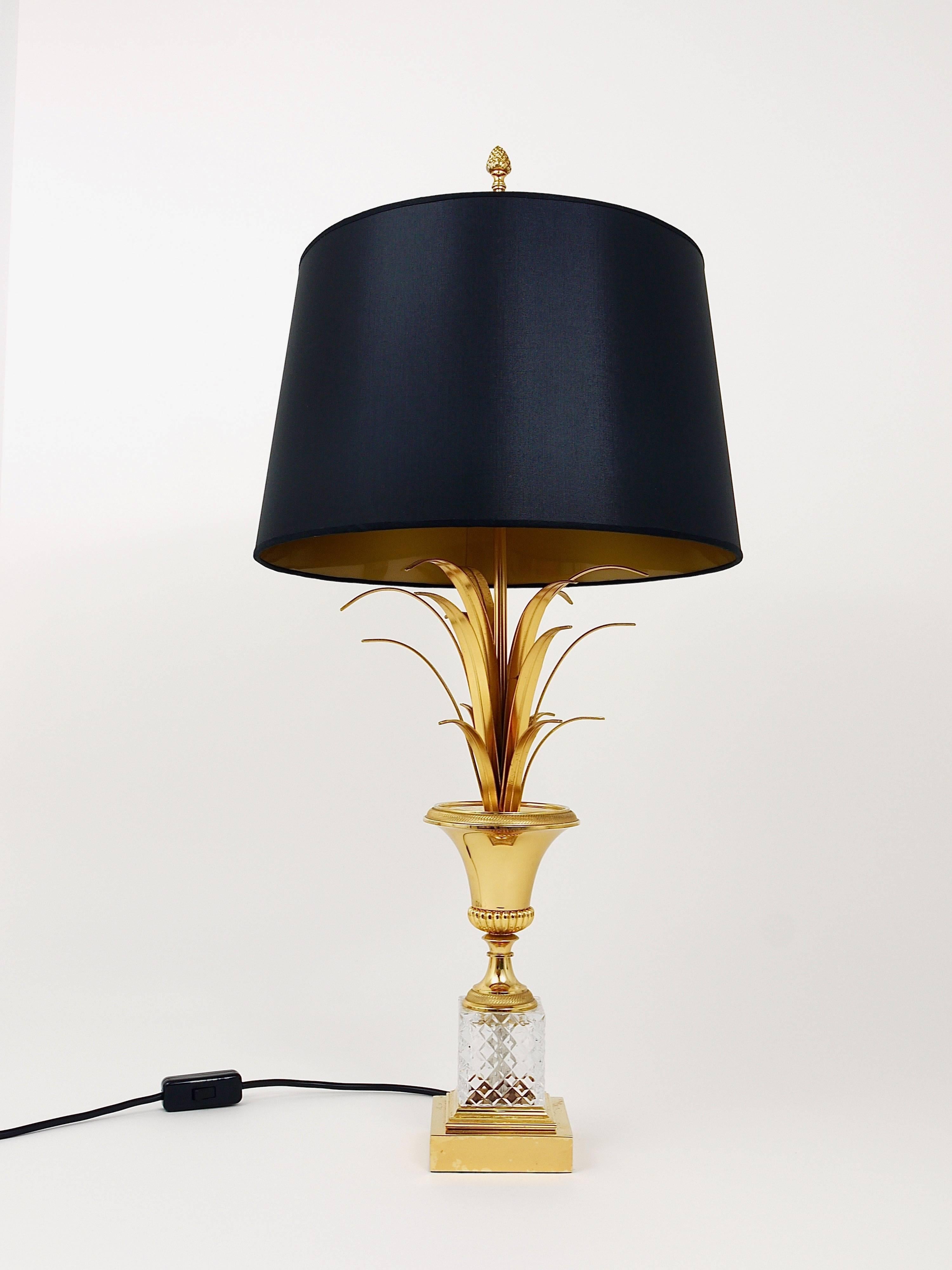 A stunning French gold-plated Hollywood Regency pineapple leaf table lamp in the style of Maison Charles from the 1970s. Crafted from gilt brass and crystal glass, it features a black lampshade with a golden interior. The lamp is in very good