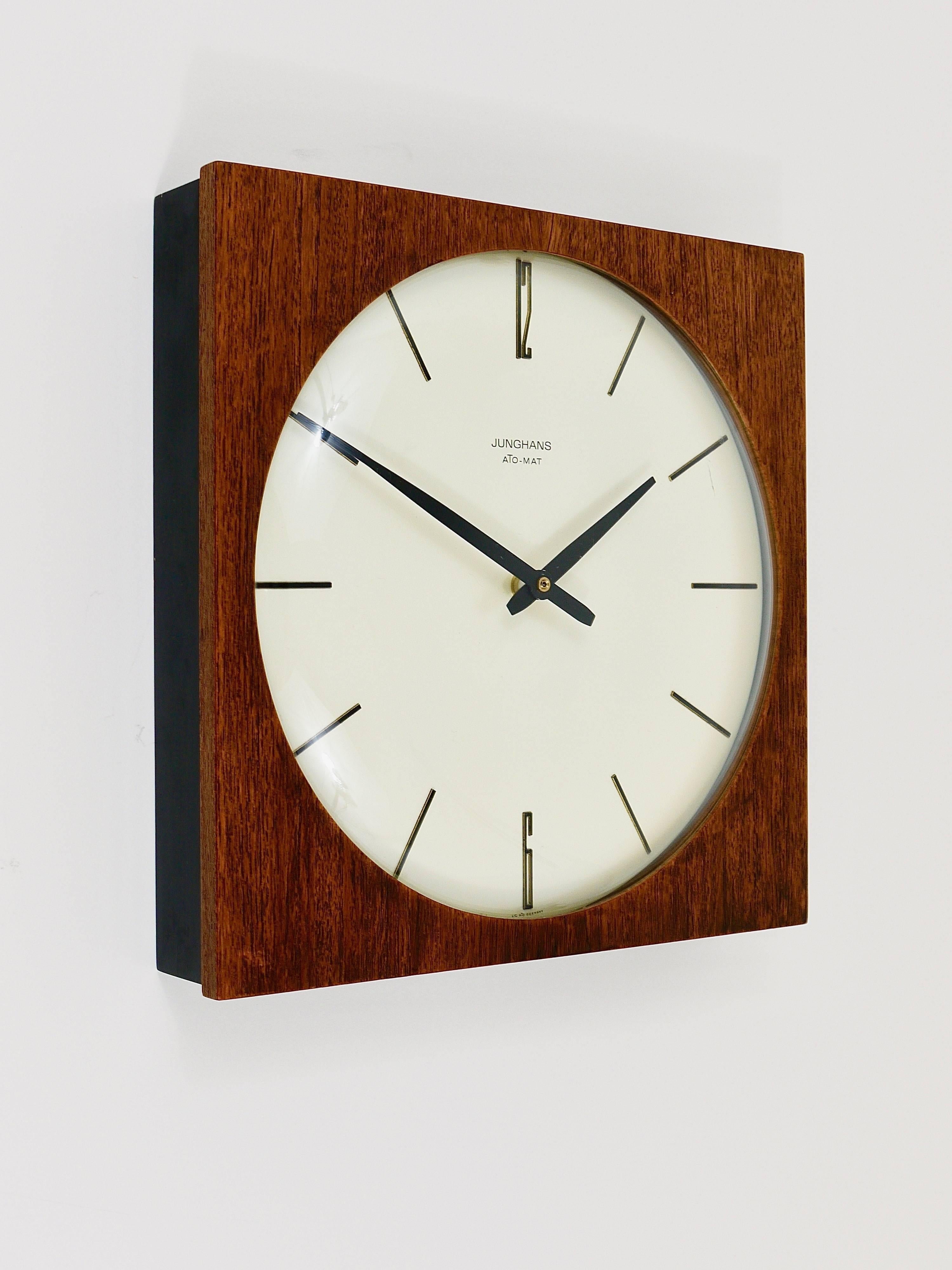 A square modernist wall clock in the style of Max Bill, executed in the 1950s by Junghans Germany. A beautiful piece with a square black and teak wood housing, a nice clocks face and handles and a domed glass. Powered by a quartz movement with a