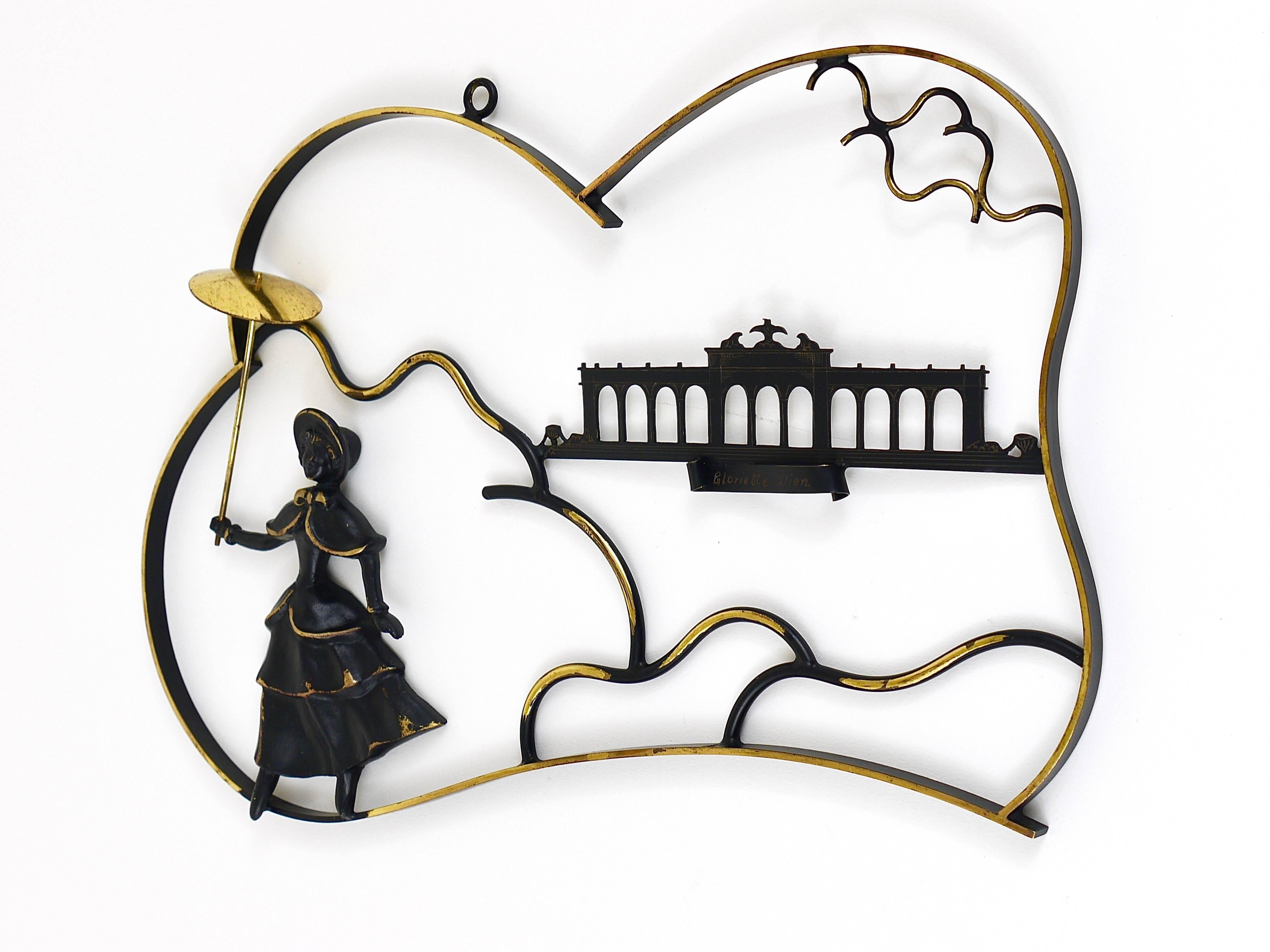 A lovely midcentury mural, displaying a woman in a Biedermeier dress with umbrella in front of the Gloriette in Vienna, all made of brass. A beautiful design by Walter Bosse, manufactured in the 1950s by Hertha Baller, Austria. In excellent