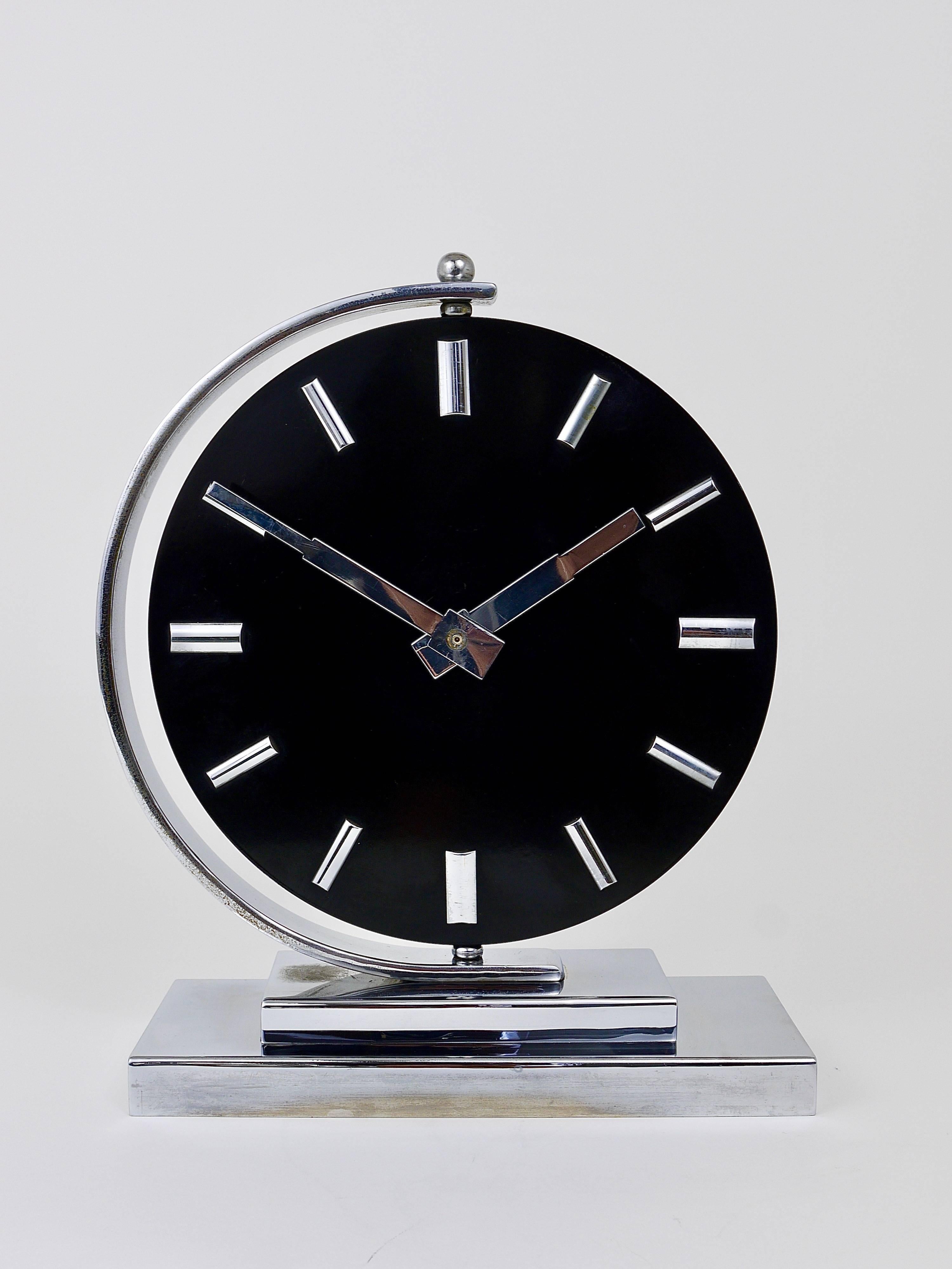 A black and nickel Art Deco table or desk clock from the 1930s, made in Germany. It has a square base made of nickel-plated brass, the black clocks face is 360 degrees rotatable, the hands and indices are also nickel-plated. Powered by a quartz