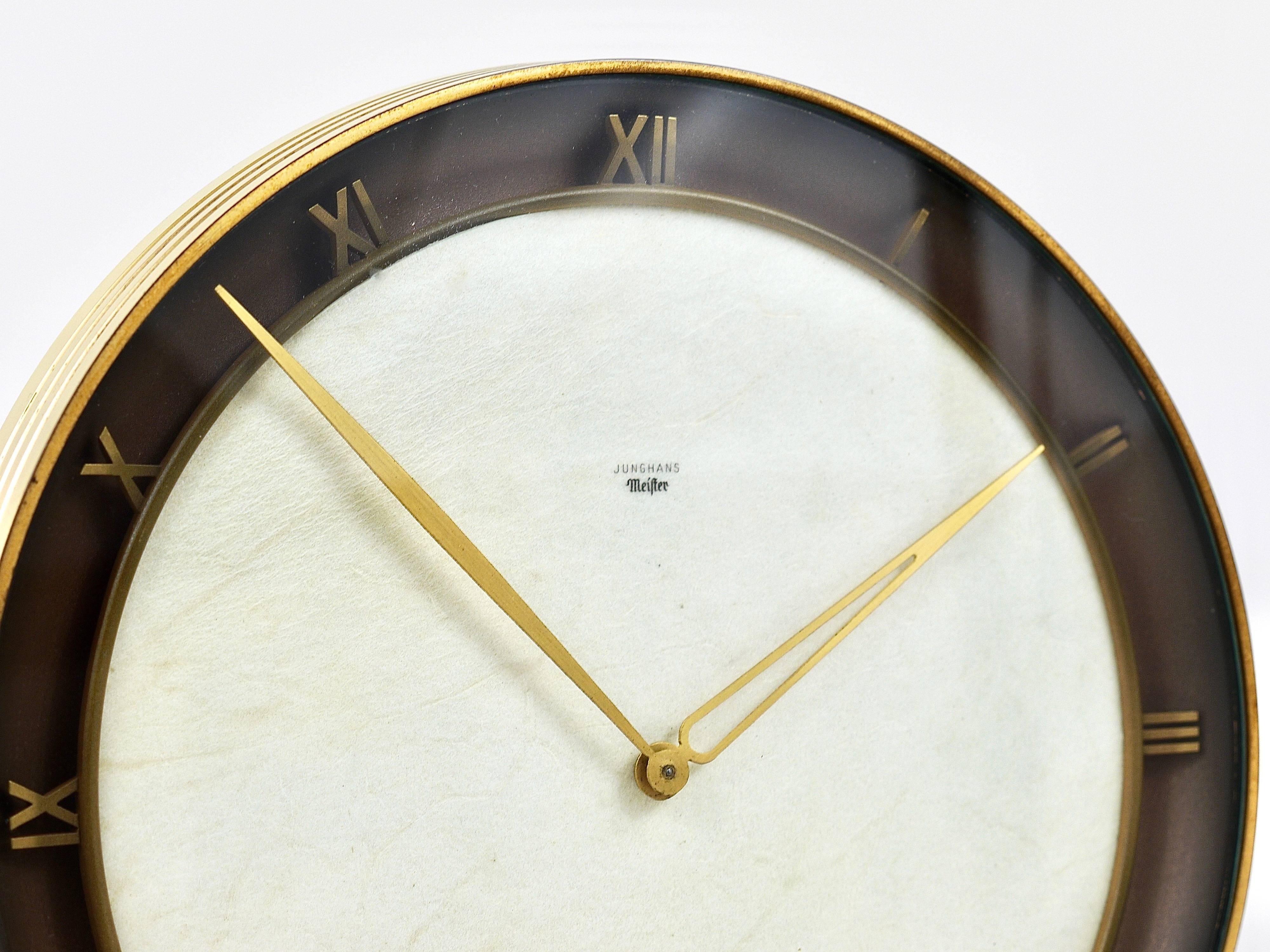 An elegant and solid Junghans Meister Art Deco desk or table clock with a mechanical 8-days movement from the 1930s. Executed by Junghans Germany. This clock has a nice brass base and housing, a clocks face made of parchment paper and beautiful