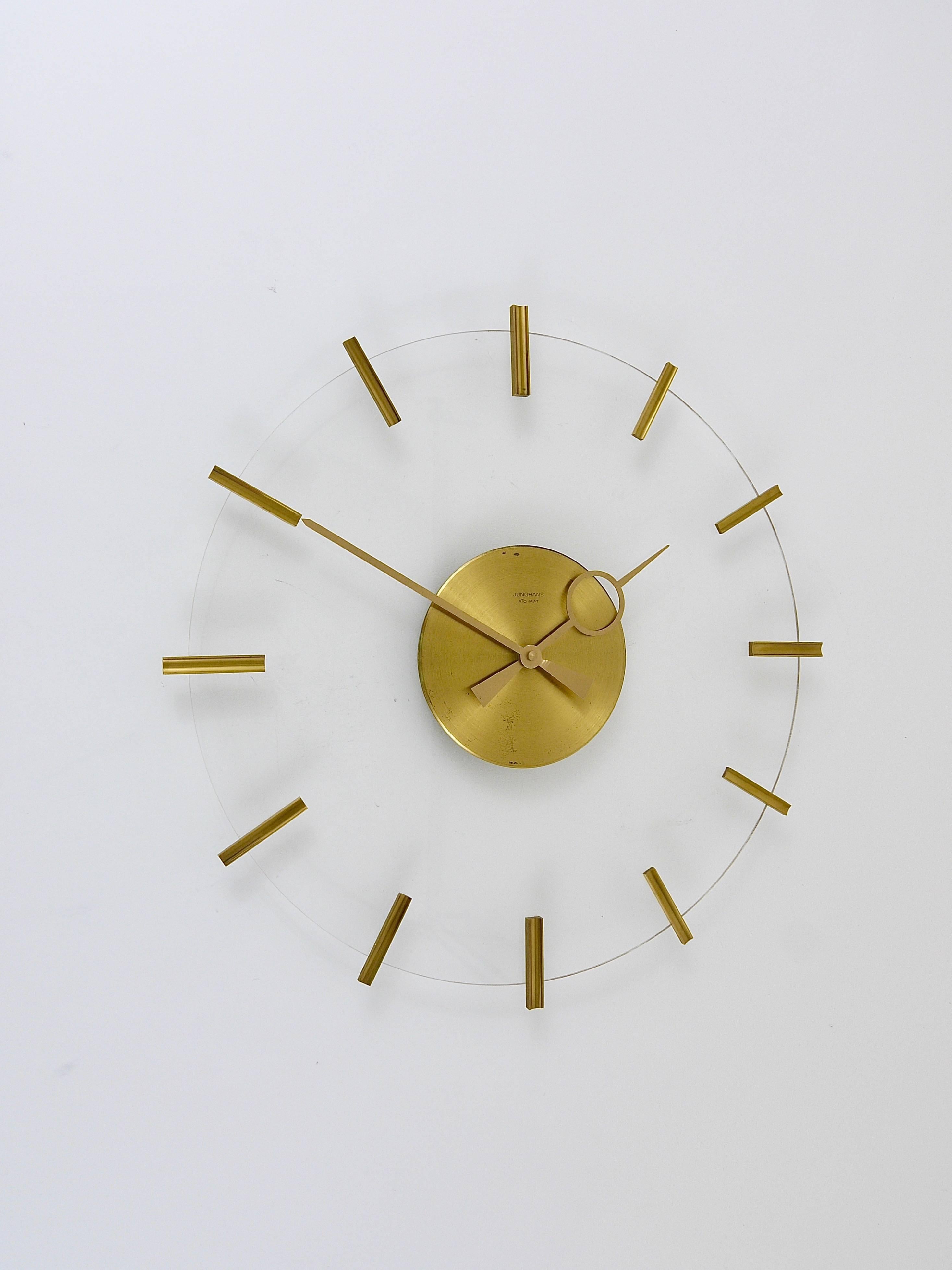 A beautiful round modernist wall clock from the 1950s, executed by Junghans Germany. The clocks face is made of plexiglass, it has nice brass indices and beautiful golden hands. Diameter: 16.5 inches. In good condition with marginal patina on the