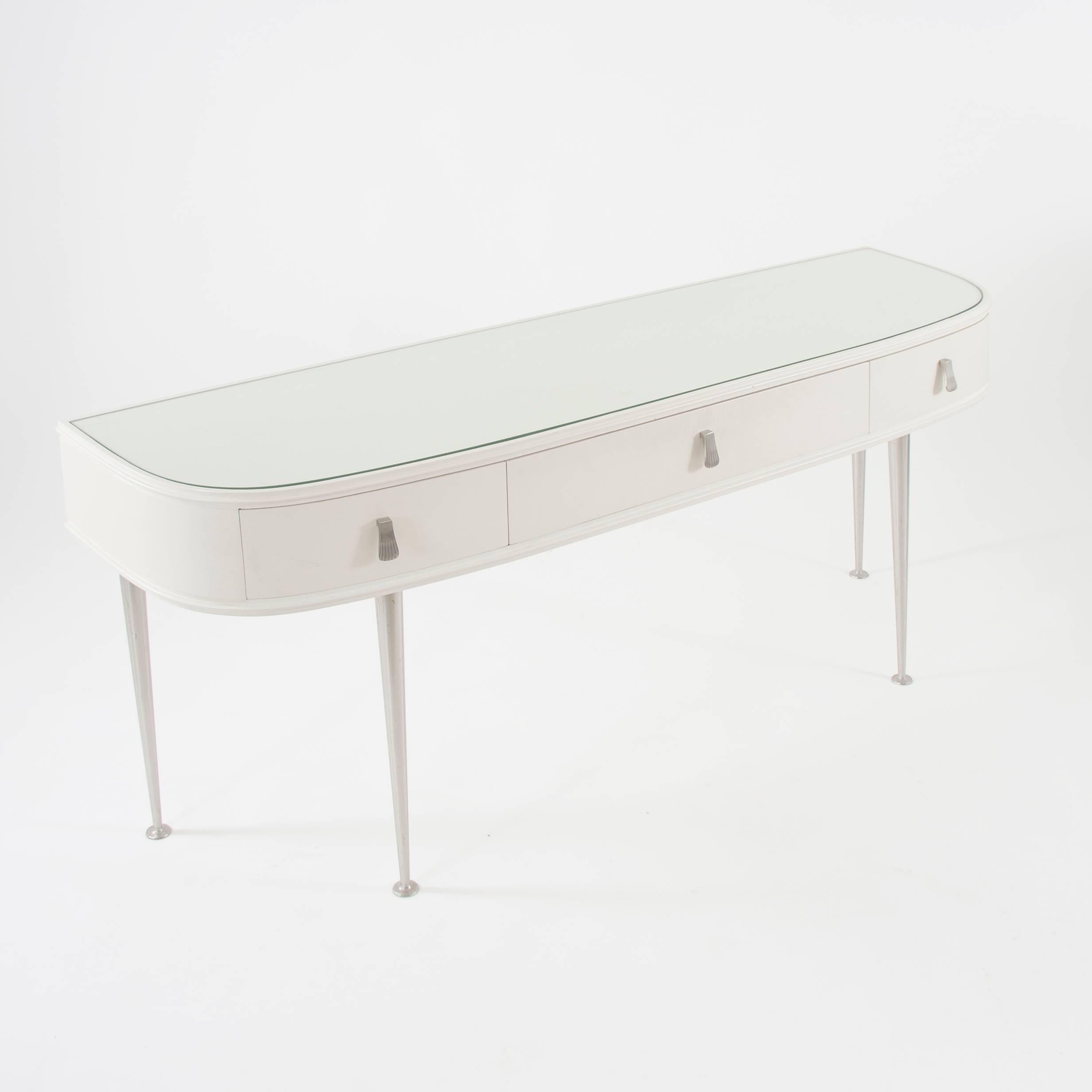 A beautiful matt-white console or vanity table from the 1950s, made in Italy. it has a glass top and three drawers with lovely handles. Very charming design. The table is in very good condition. 
We offer a matching pair of bedside tables in our