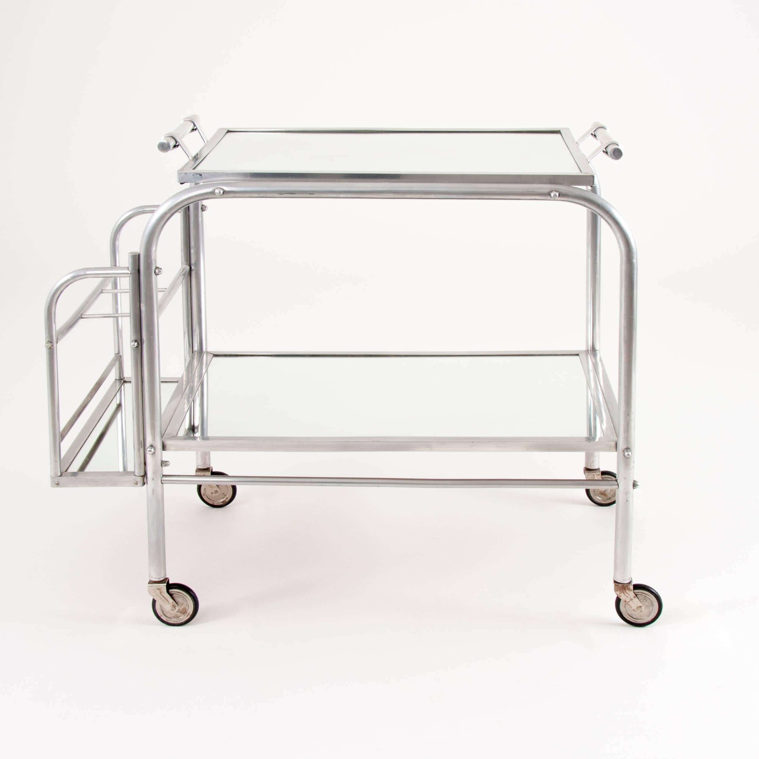 A beautiful Art Deco serving bar cart with removable mirror tray on its top from France, 1930s. In the style of Jacques Adnet. Made of aluminium, in very good condition.
