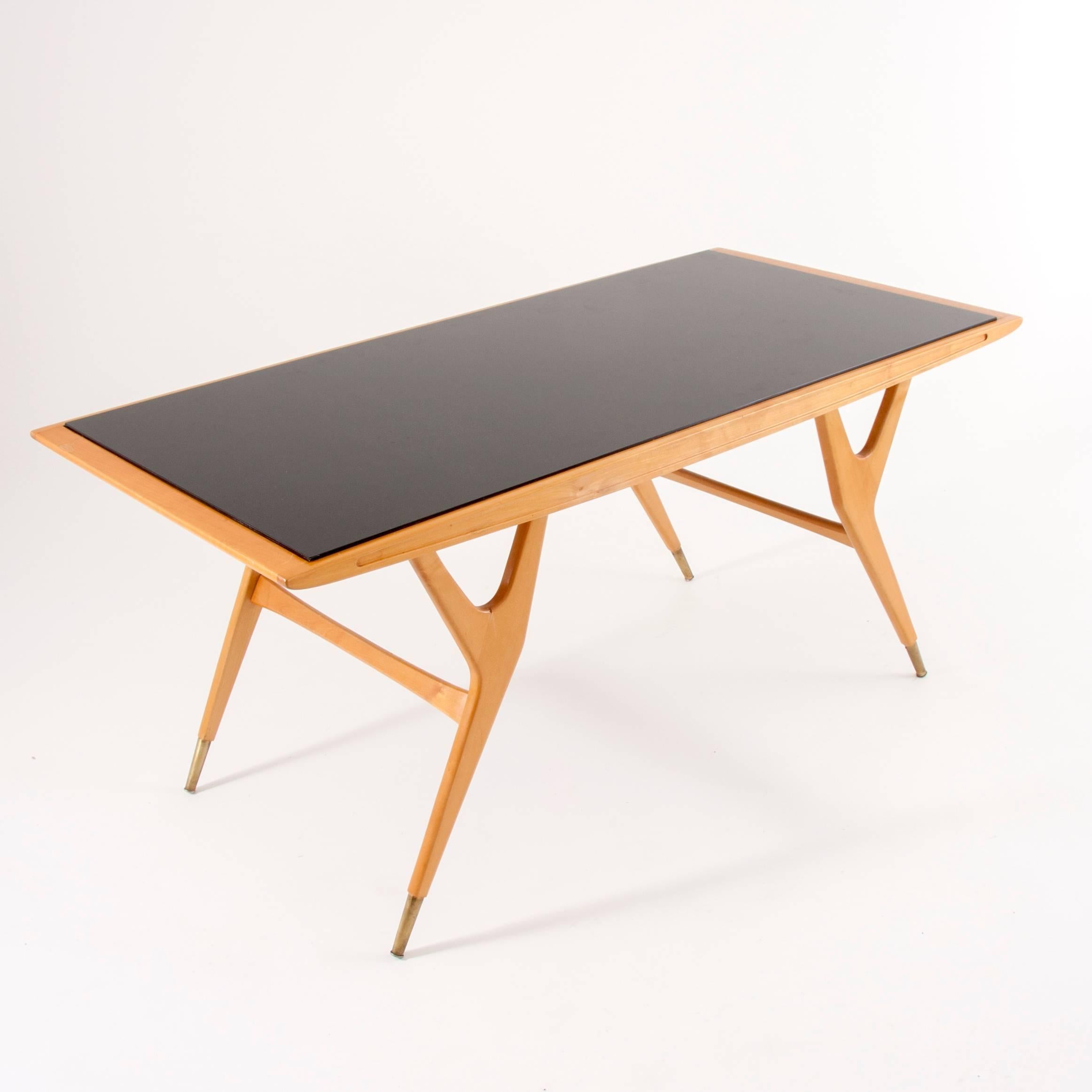 Ein schöner und außergewöhnlicher modernistischer Couchtisch mit einer schönen Form und exquisiten Details, darunter kleine konische Messingfüße. Hergestellt aus Holz mit einer Platte aus geschwärztem Glas. Hergestellt in Italien in den 1950er