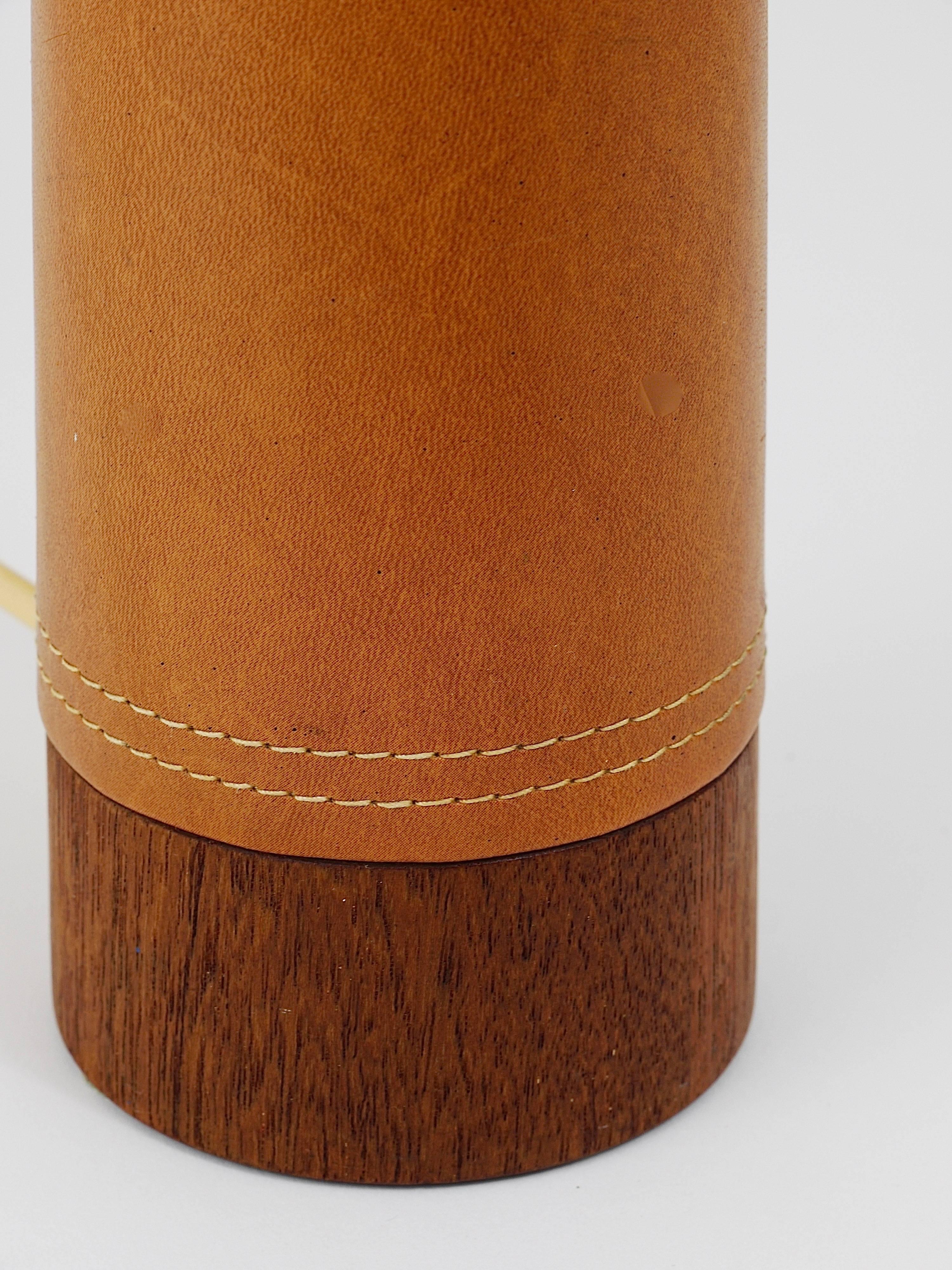 Une belle et minimaliste lampe de table ou d'appoint moderniste scandinave des années 1960, conçue et fabriquée par Bergboms Suède. Elle présente une base conique en teck, élégamment recouverte de cuir cognac brun moyen, et est surmontée d'un