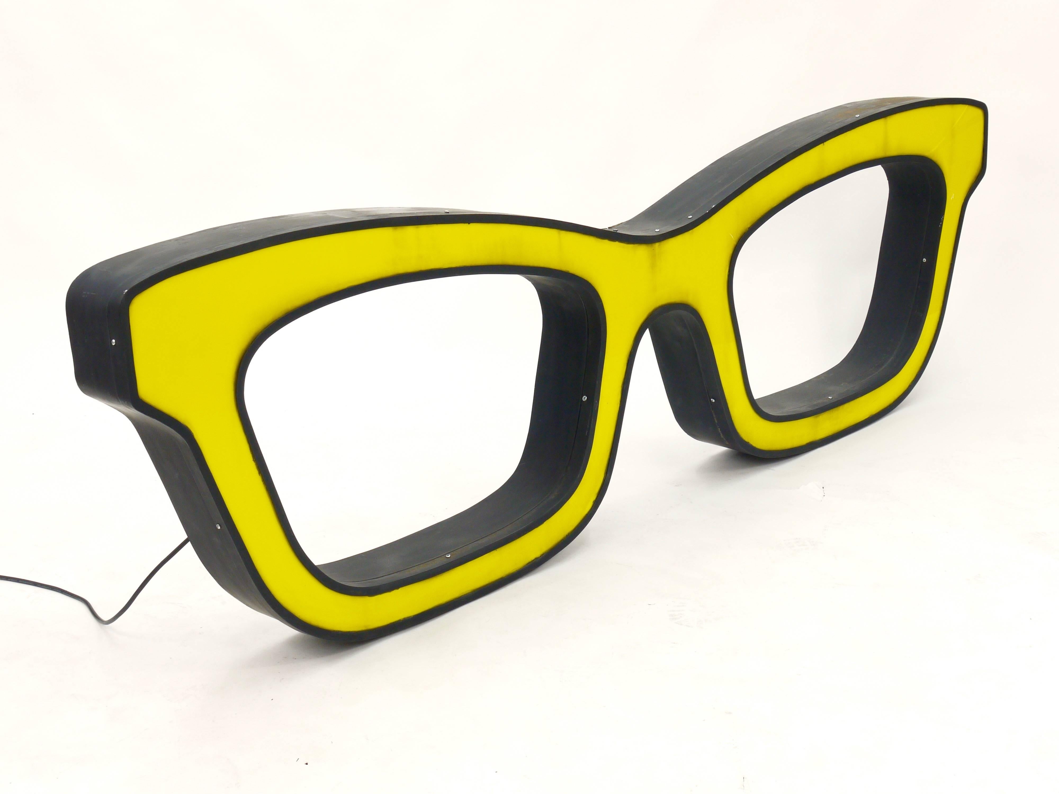 A big yellow illuminated advertising sign displaying glasses / spectacles. Made in the 1960s. 70