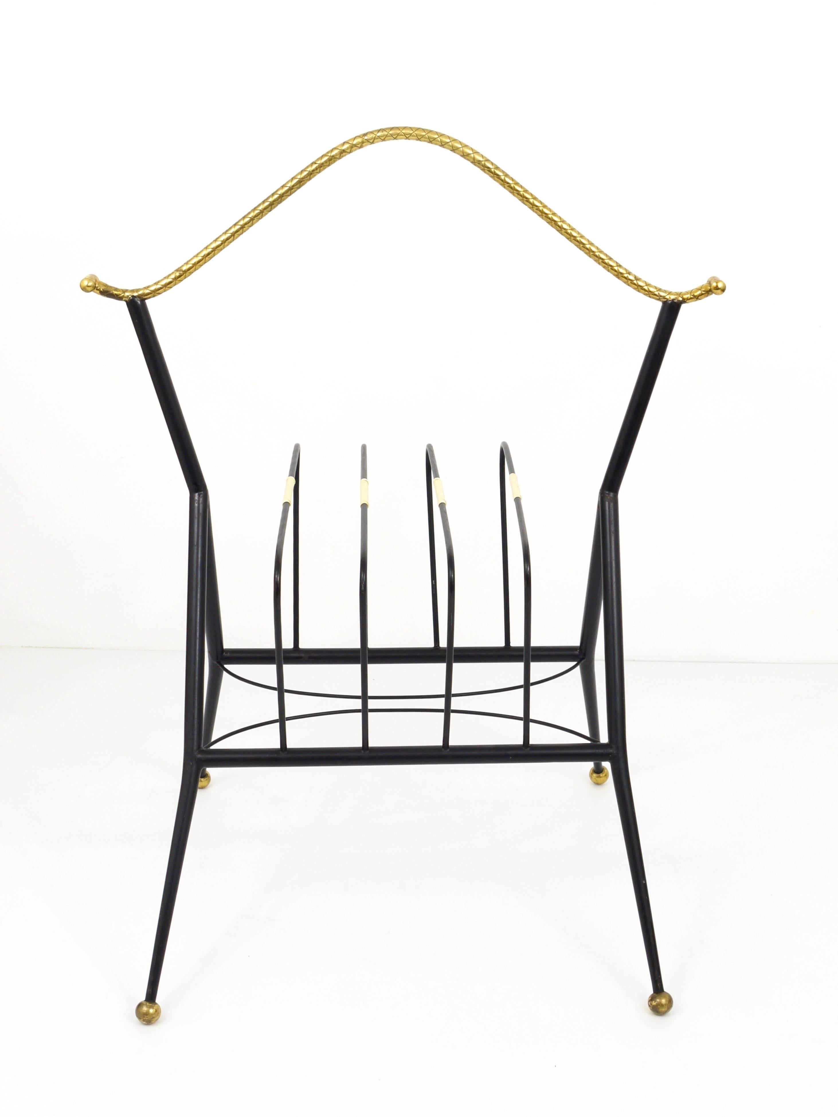 A beautiful French record rack or magazine stand from the 1950s in the manner of Maison Charles. Made of black iron with nice brass details. In very good condition.