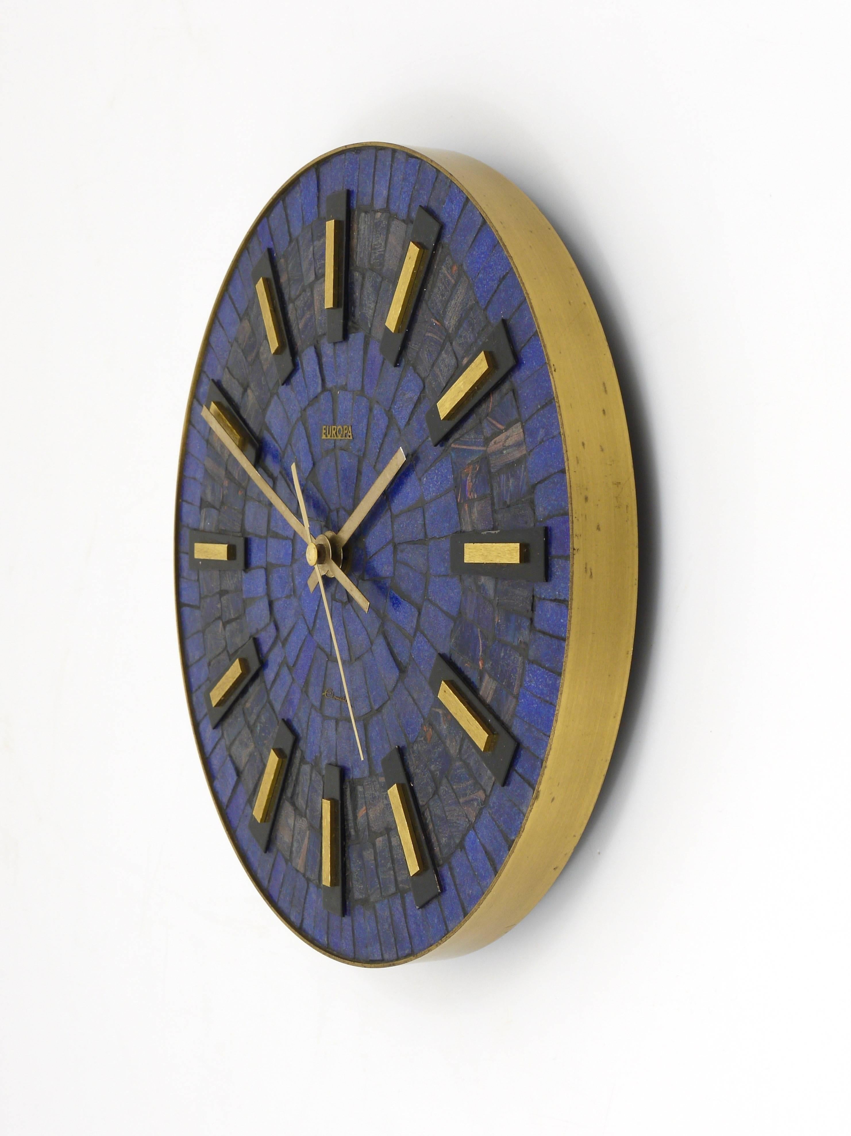 A beautiful round Mid-Century wall clock, with nice brass hands and indices and a stylish blue mosaic clocks´ face. Executed in the 1950s by Europa, Germany. Original battery-operated movement. In very good condition.