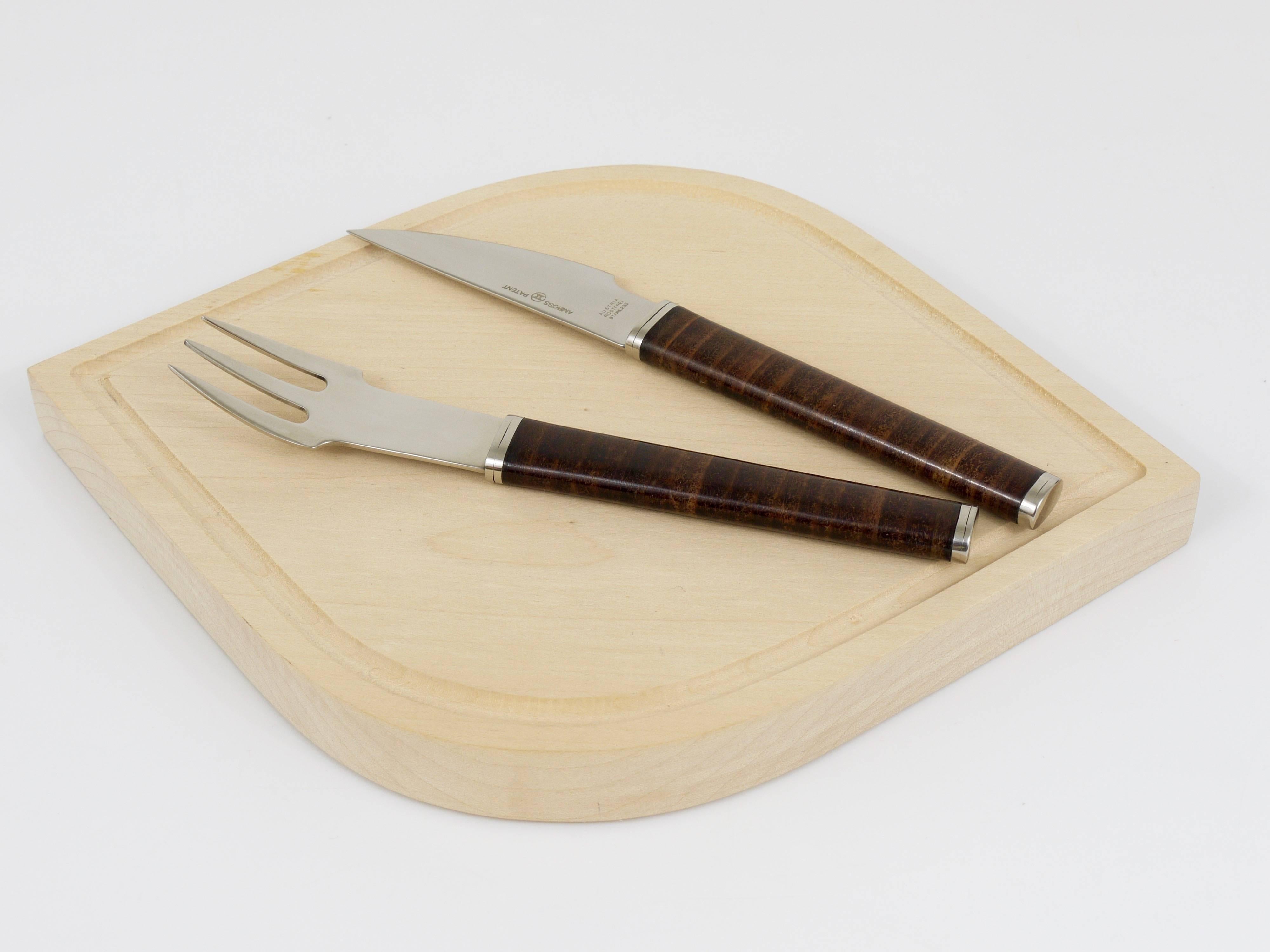 A beautiful Mid Century design snack set, consisting of a fork and knife and a wooden board, designed by János Megyik. Executed by Amboss Austria, who collaborated with a lot of Austrian designers and architects, like Carl Aubock. The flatware is