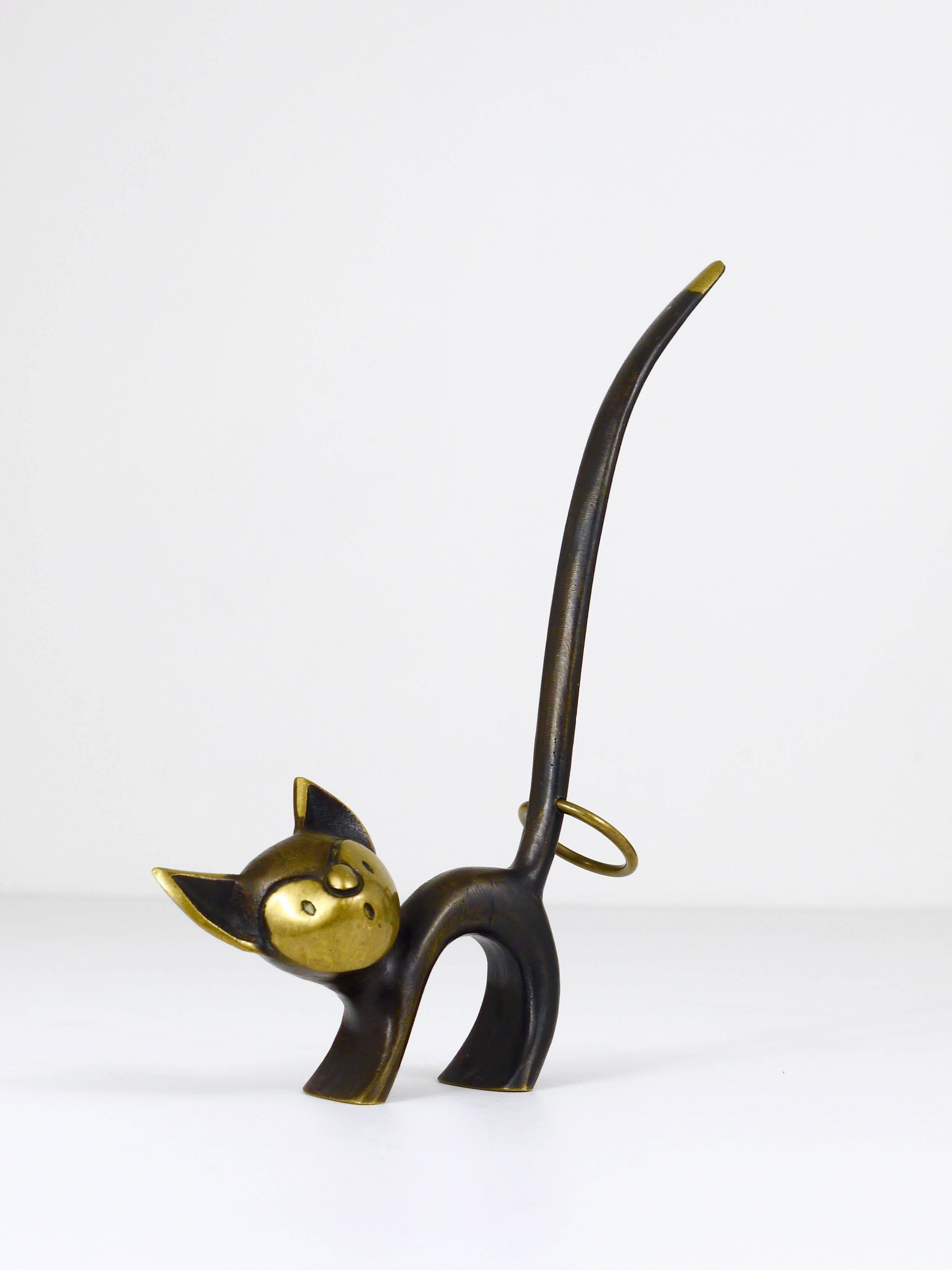A charming Austrian brass cat figurine usually made to be used as a pretzel holder, a decorative piece, very suitable as a ring holder. A very humorous design by Walter Bosse, executed by Hertha Baller, Austria in the 1950s. Made of brass, in very