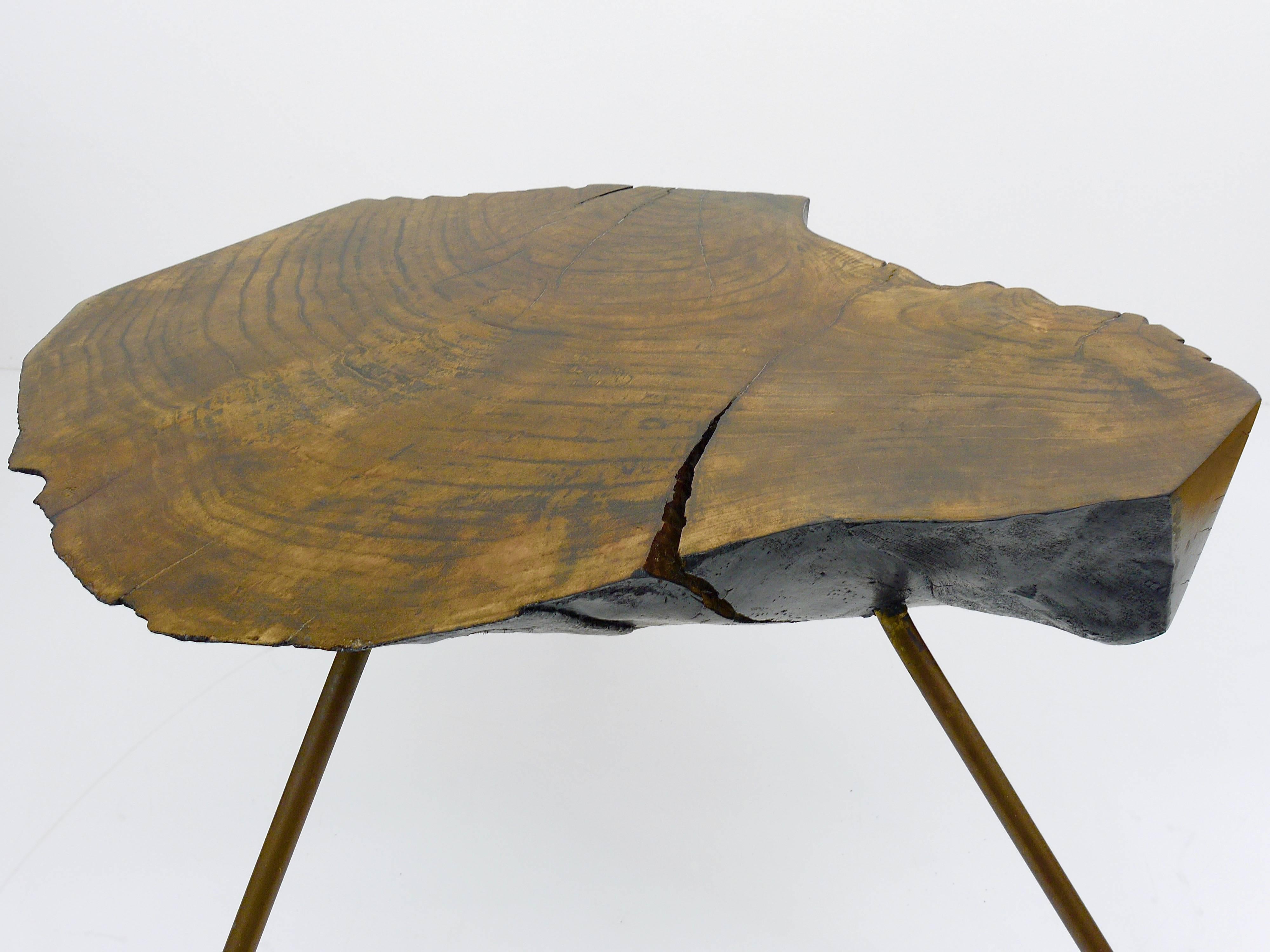A beautiful Viennese tree trunk table, designed and executed by Carl Auböck in the 1950s. Made of a walnut wood slab, black painted bottom, with three brass legs and rubber shoes.