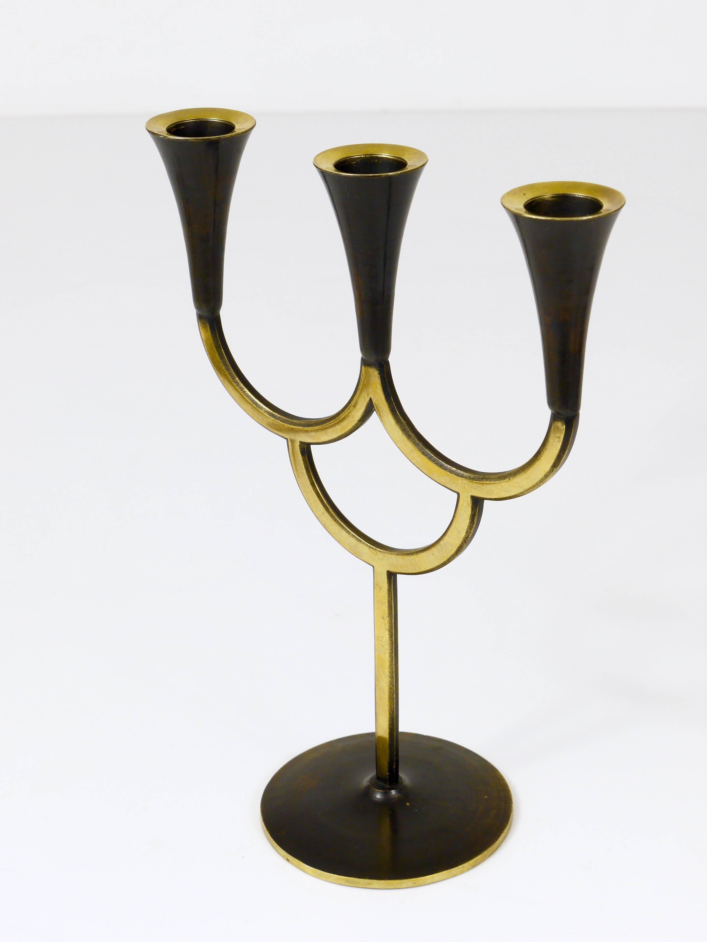 A beautiful Austrian modernist three-arm candelabra  candleholder / candlestick, made of brass, partly black-finished. Designed by Richard Rohac, manufactured by Atelier Rohac in the 1950s, Vienna, Austria. Marked on its bottom, excellent condition.