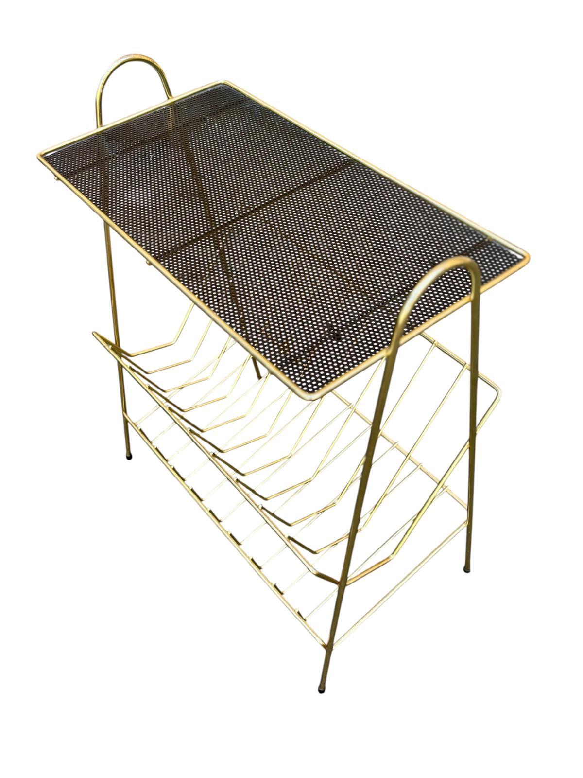 Revistero francés Circa 1.950, diseñado por Mathieu Matégot, diseñador industrial húngaro-francés en los años 50.
Realizado en latón dorado y con una base metálica negra perforada.