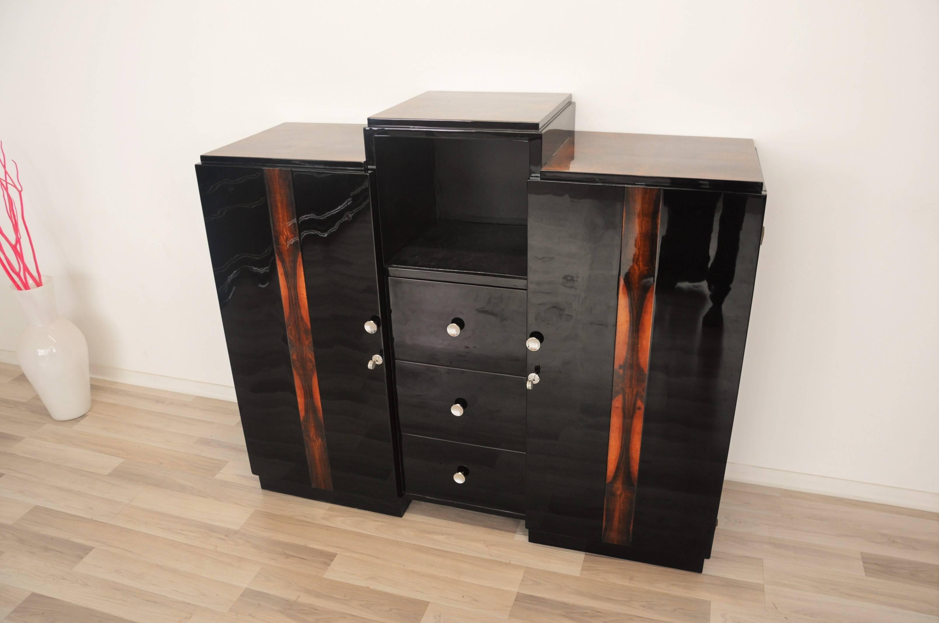 Highgloss black Art Deco commode or small highboard refined with elegant chrome handles. On the doors and the top surface you will find unique walnut wood details who offer a very special ambience.

- open storage compartment in the middle
-