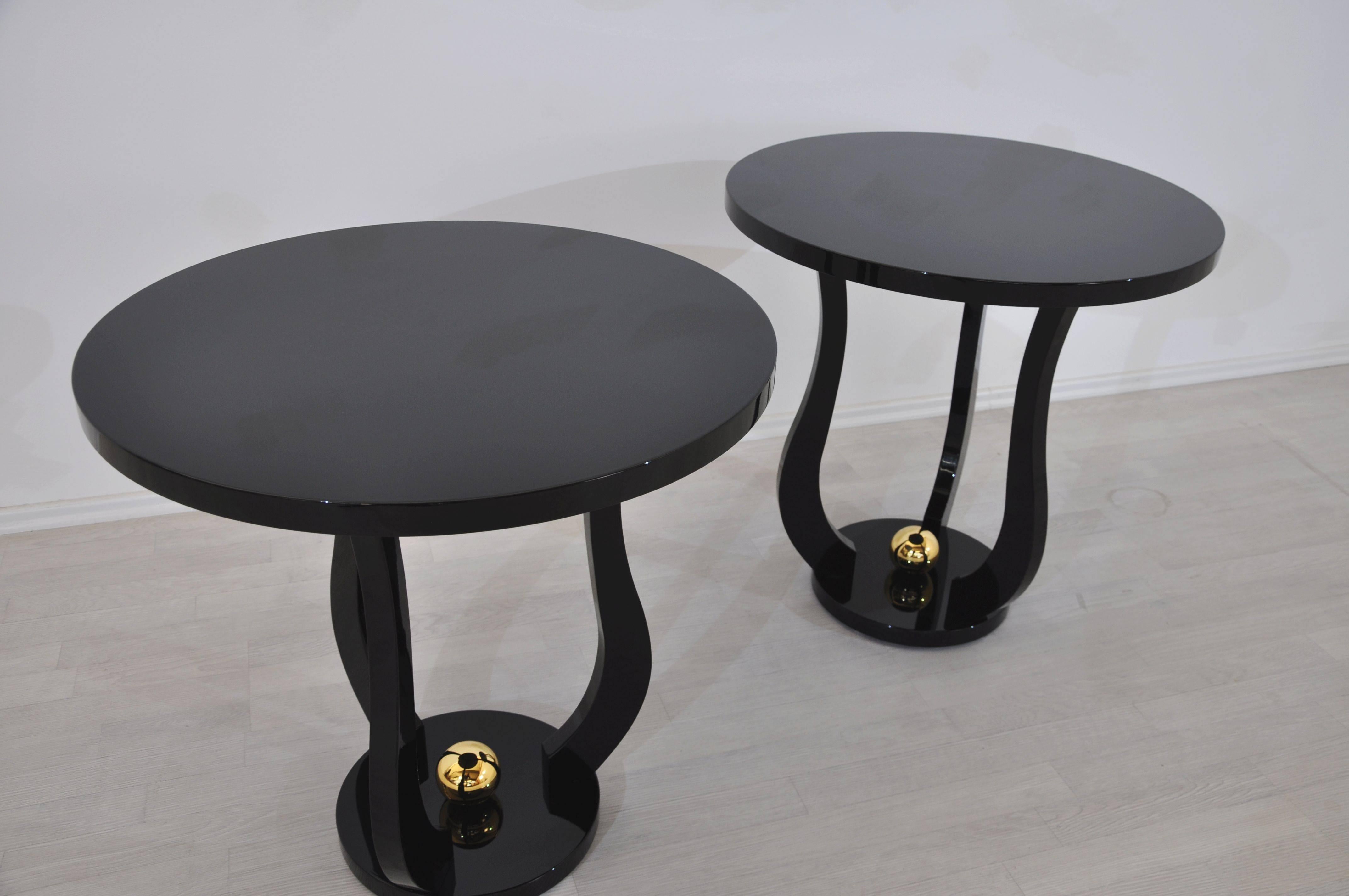 This pair of side tables with a beautiful shape are reminiscent of the great Art Deco body language.  It offers a simple high gloss black paintjob combined with a central golden ball for an eye-catching experience.

- Wonderful curved legs
- high