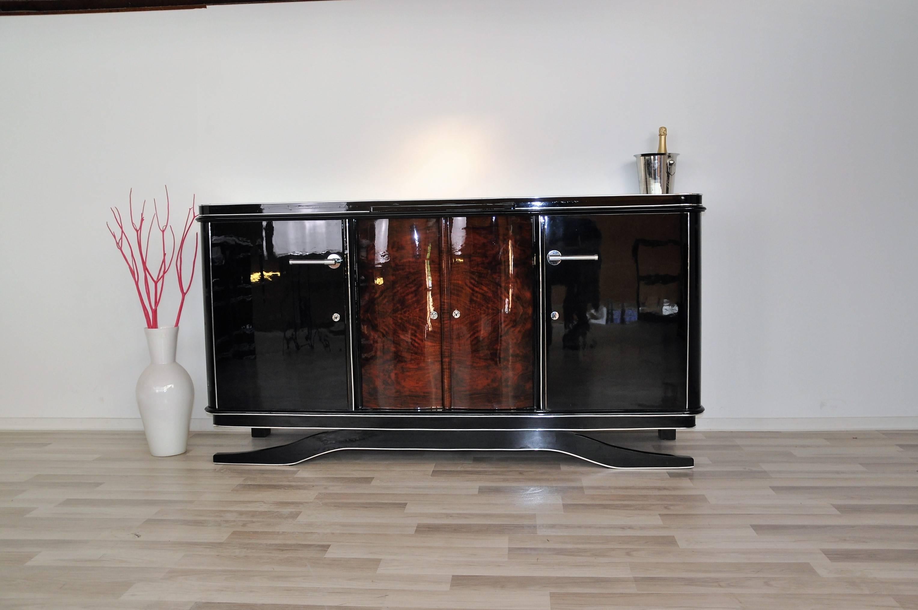 Free floating Art Deco buffet with a wonderful walnut door. The simple and plain piece of furniture inspires with its curved walnut door in the middle compartment. It also offers chrome handles and handpolished piano lacquer.

 Fine chrome bars