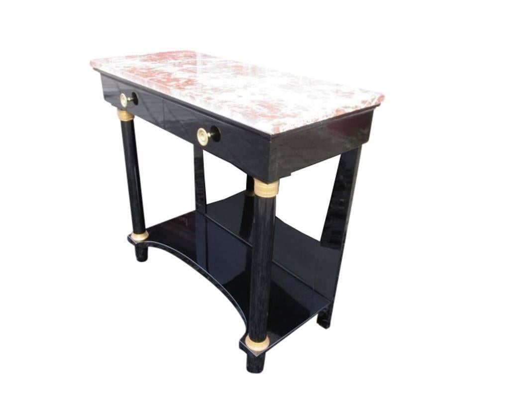 The Empire console with mahogany veneer is painted with black lacquer and high gloss polished. The two drawers, the columns, the marble and the brass applications give the console the perfect look.

Columns with brass capitel
Restored and in good