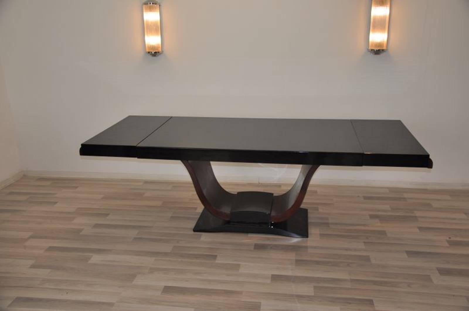 A stunning rosewood dining table expandable up to 91 in. Original single piece from Saarland, Germany. Build in the 1930s it offers a wonderful curved foot that leads to a high gloss black top plate. The floating design makes it a unique and