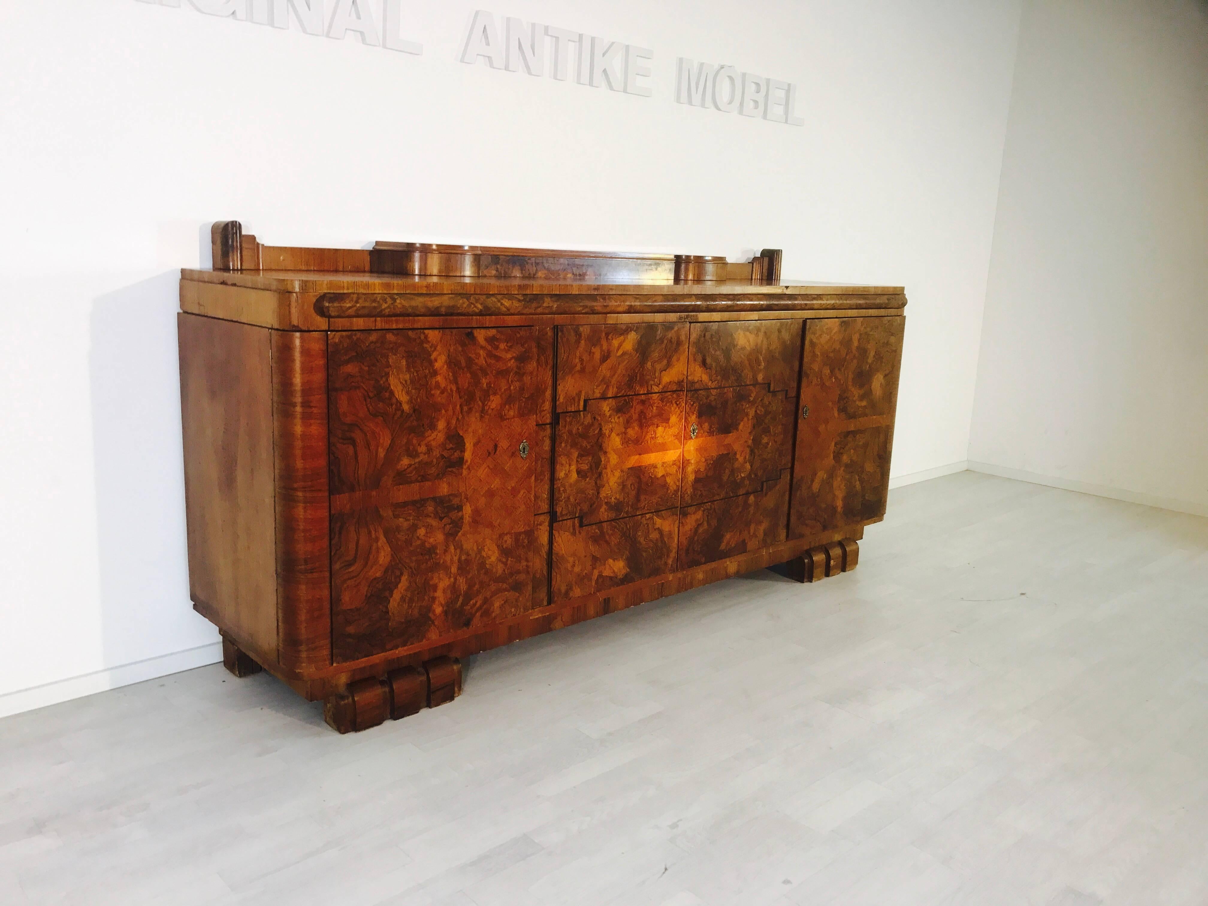 An Art Deco sideboard in walnut wood. Remarkable is the unique grain with the marvelous marquetry on the doors. As can be seen in the pictures, there is a lot of storage space in the interior of the piece of furniture with various storage