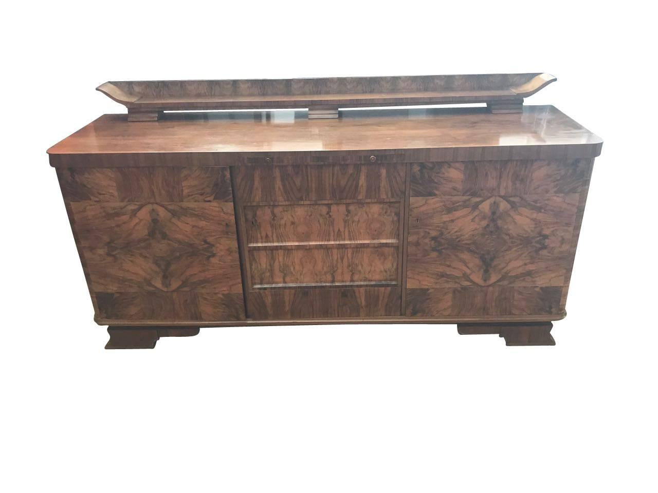 An Art Deco sideboard from France. The 1920s furniture has a walnut veneer with unique grain. The interior offers great storage space, as well as different storage possibilities. The straight-lined design combined with the elegant attachment / hutch