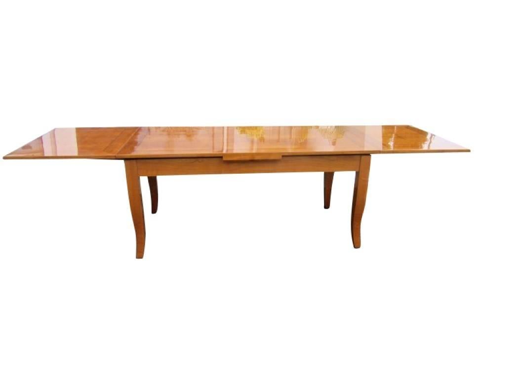 A dining table in Biedermeier style made of cherrywood and ebony. The big table is simple but elegant following that this piece fits perfectly into every living/dining room. Pulled out with one plate the table extends to 250 cm and with two plates