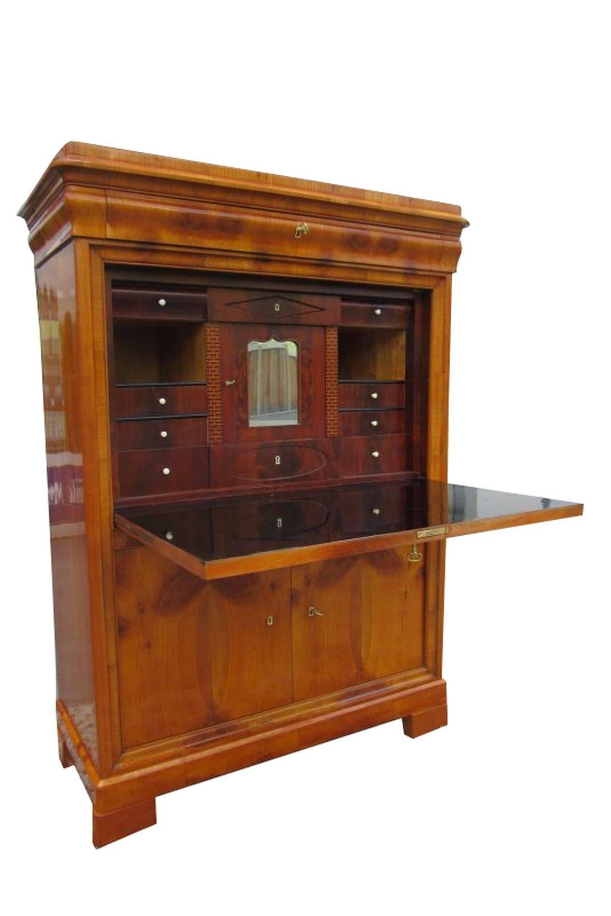 A Biedermeier Secretaire made of cherrywood. The corpus is made of softwood veneered with cherrywood. It has five compartments and a cabinet. Opening the cabinet reveals eight more drawers, two free compartments and a small door with a mirror. The