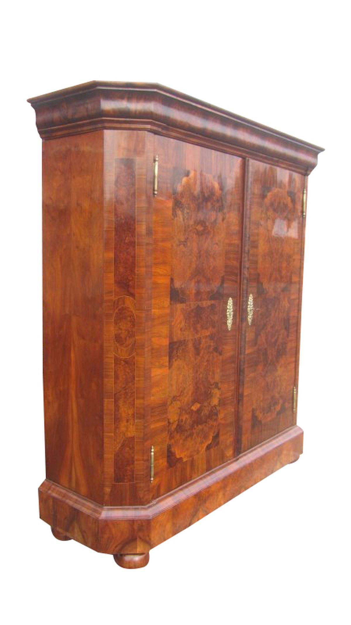 A wardrobe from the Baroque period. This piece is made of softwood and veneered with walnut wood and has birch thread inserts. The surface is hand polished and shines in a unique brown-black grain. It has original keys and keyholes. The inside was