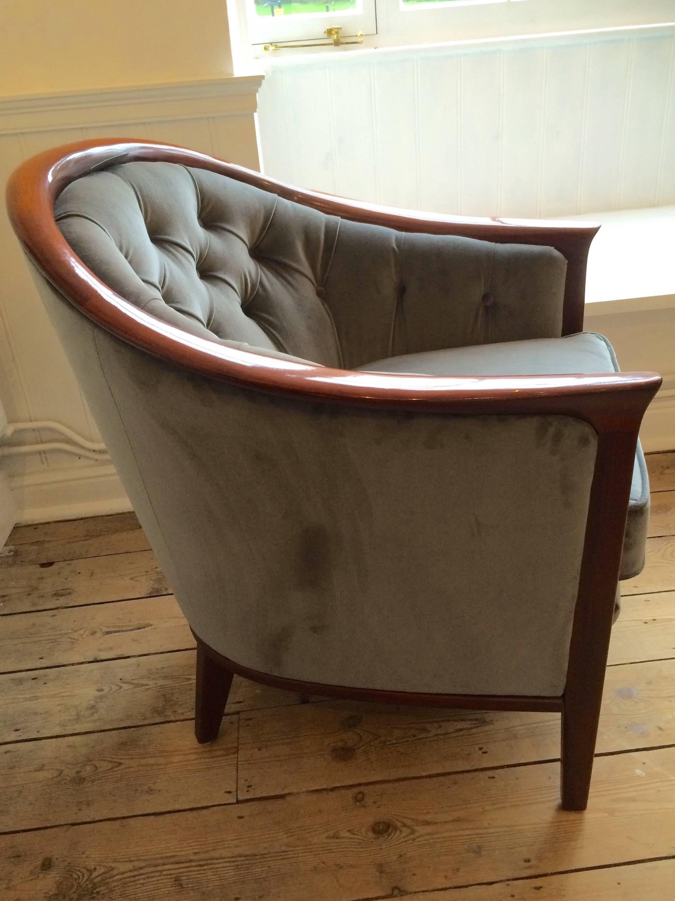 Rounded form with sweeping arms, upholstered in Pierre Frey Opera grey velvet with button detail.